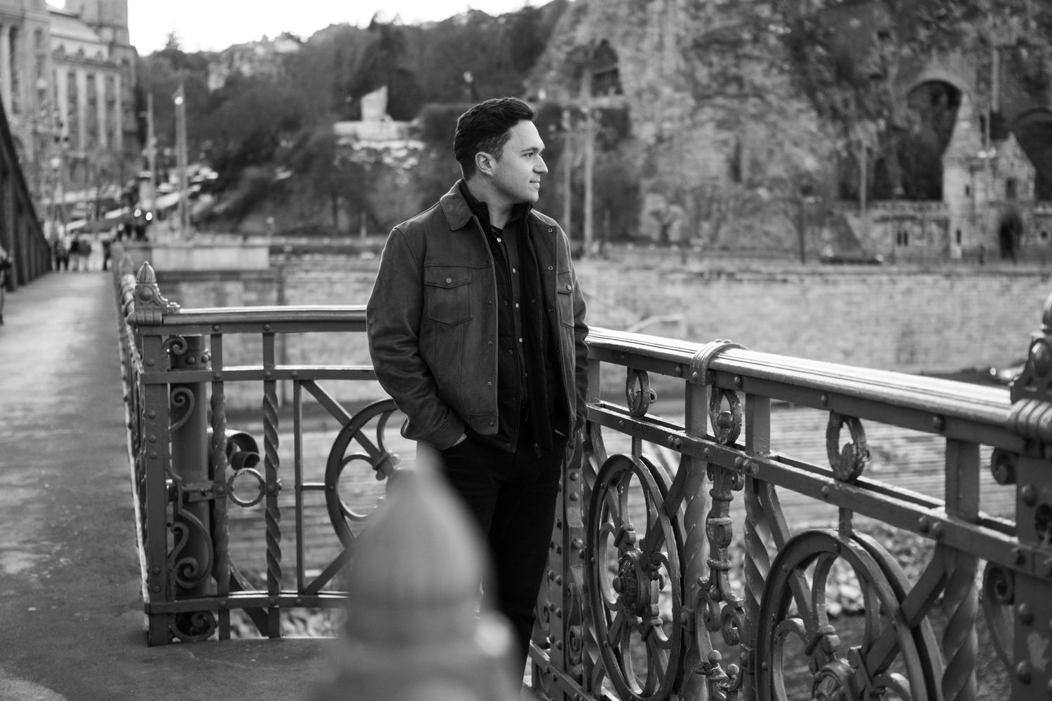 Outdoor portrait series with ornate metal railing and natural landscape in background.