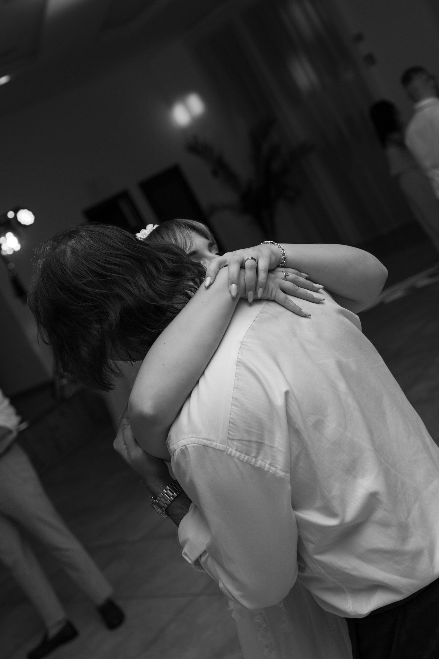 Black and white photo of dancers embracing during wedding reception.