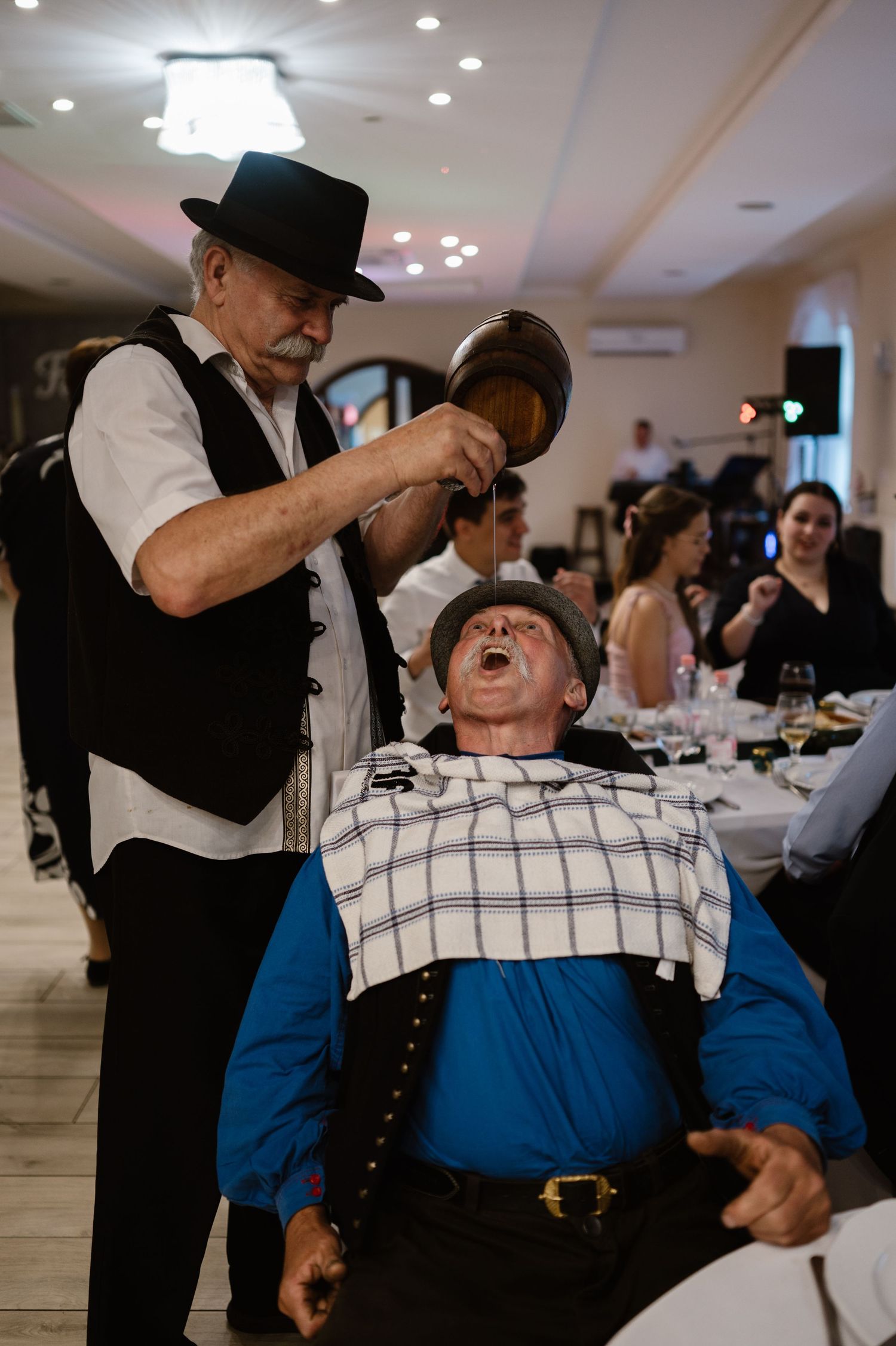 Guests share drinks and laughter during indoor wedding celebration.