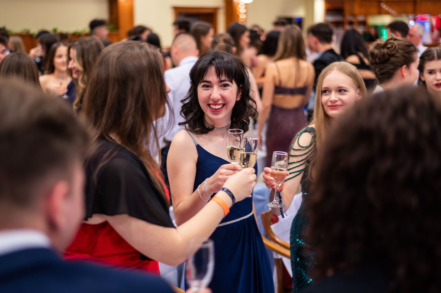 Lively crowd enjoying themselves at an indoor celebration with drinks.