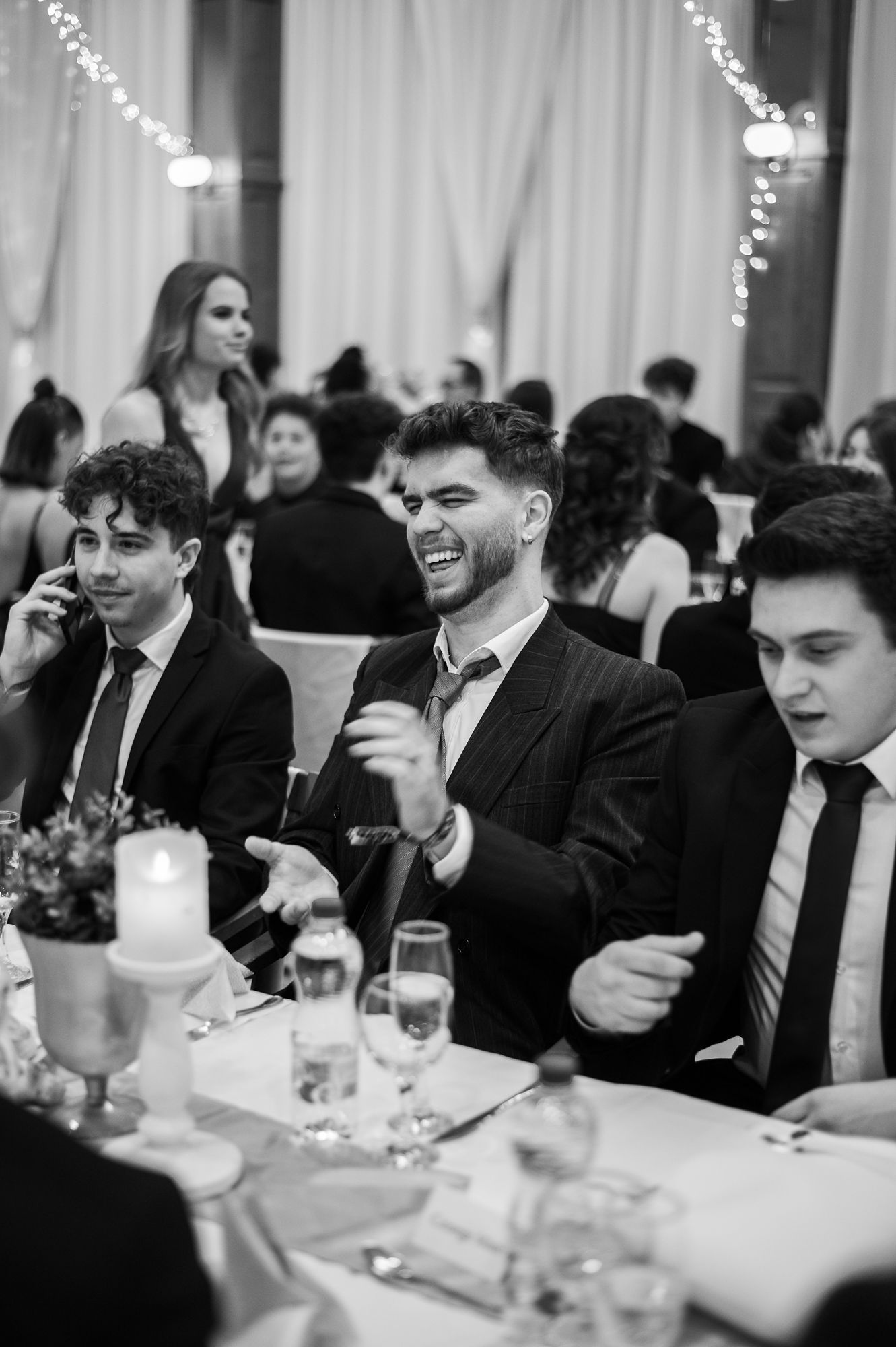 Guests laughing and socializing at formal dinner tables during an elegant evening event.