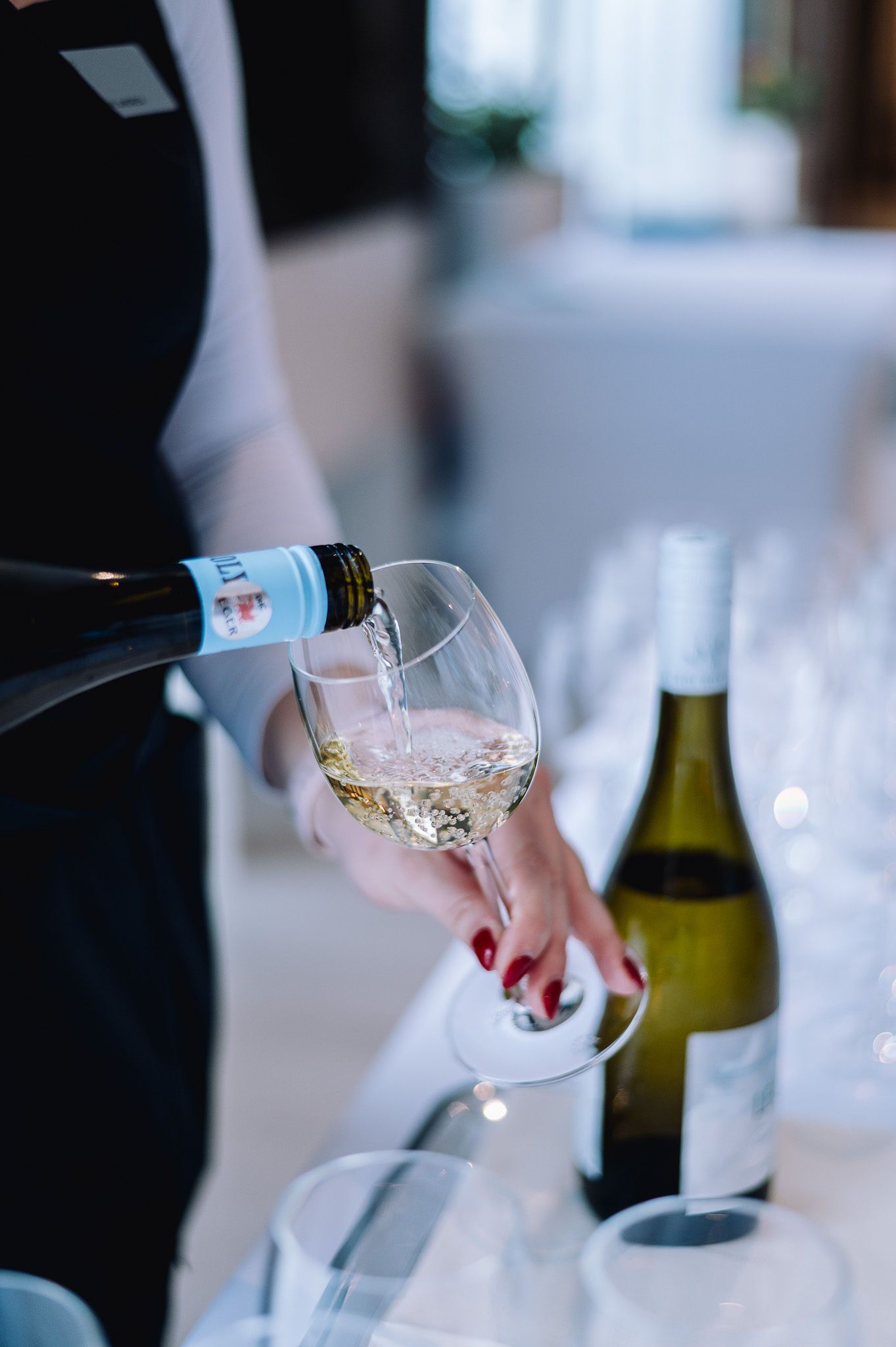 Hand pouring wine into crystal glasses at an elegant event.
