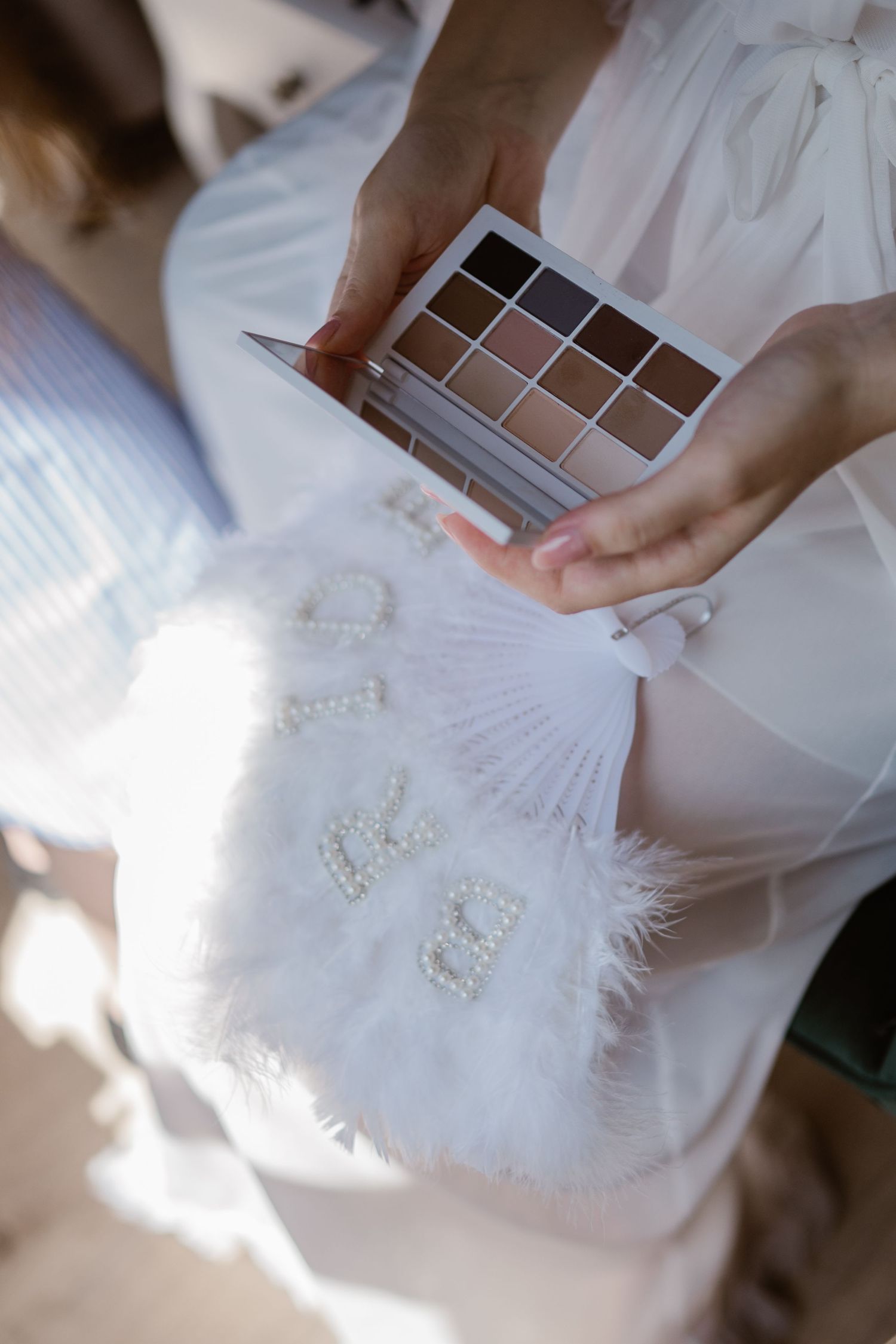 White wedding accessories and details arranged on a soft fabric background.