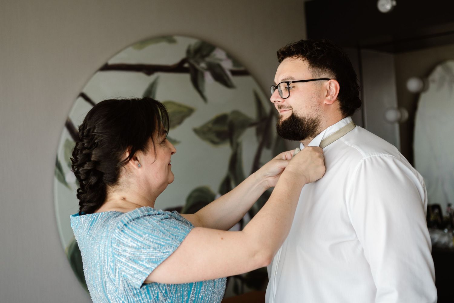 A touching moment of wedding preparation as a tie is being adjusted.