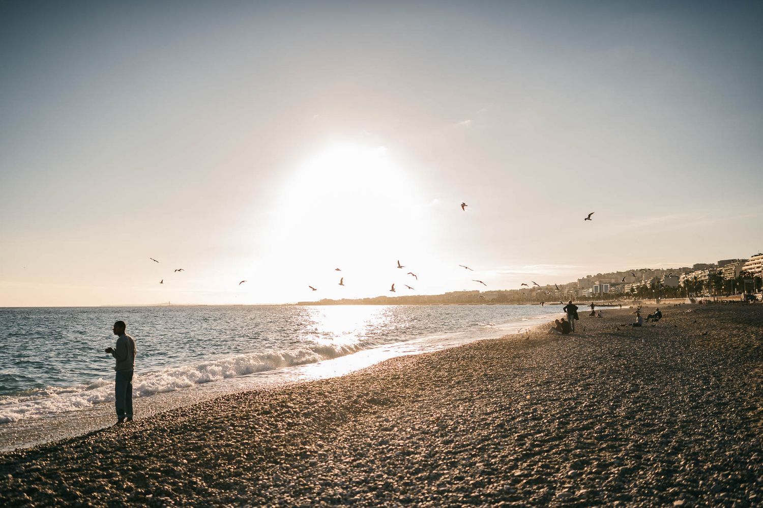 Sunset view of a peaceful beach with silhouettes against golden light.