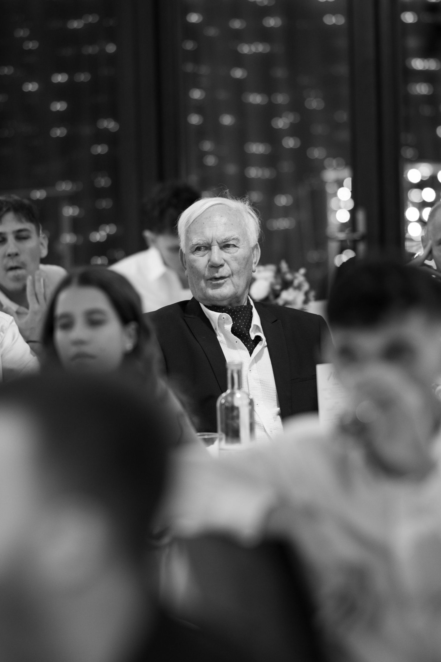 Black and white candid shot of wedding reception guests during evening celebration.