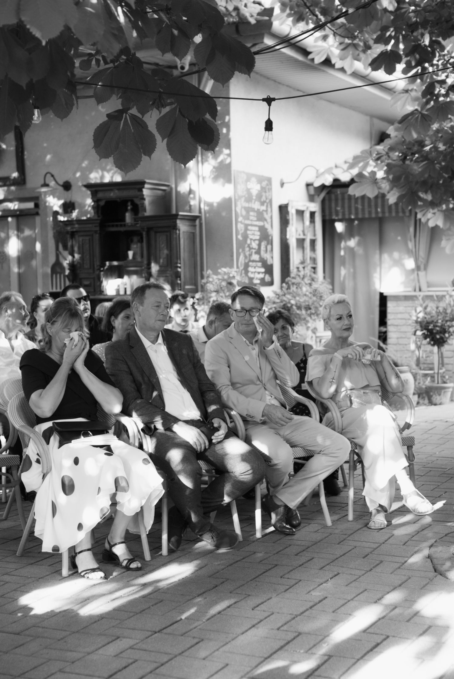 Black and white photo of wedding guests seated outdoors during ceremony.