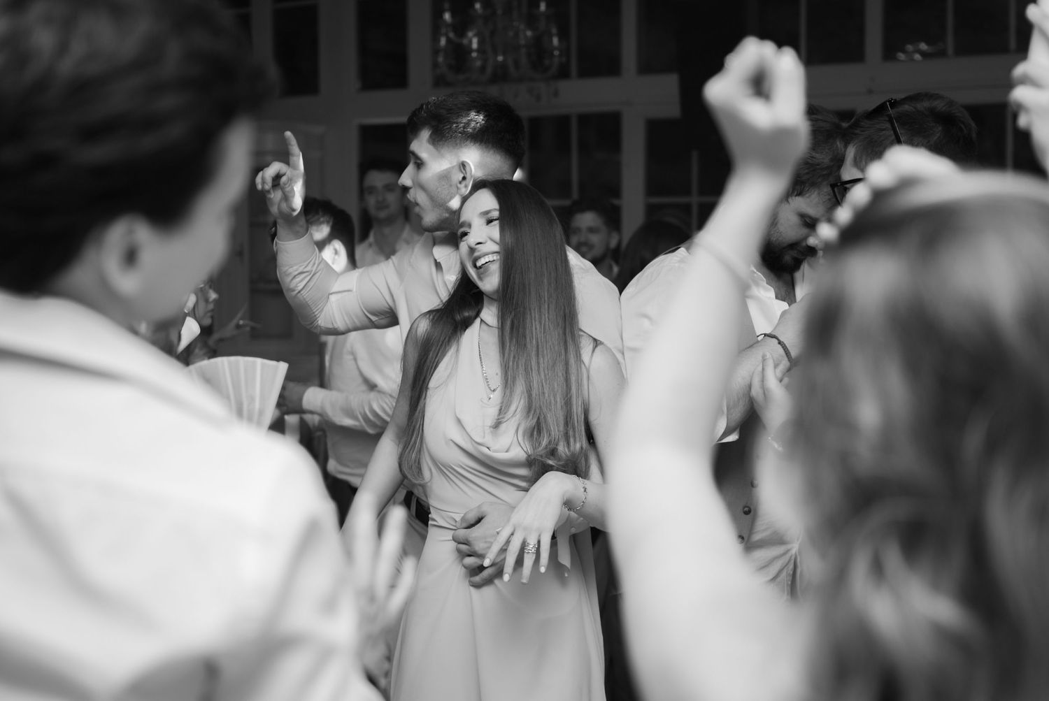 Black and white photo of guests dancing joyfully at a wedding reception party.