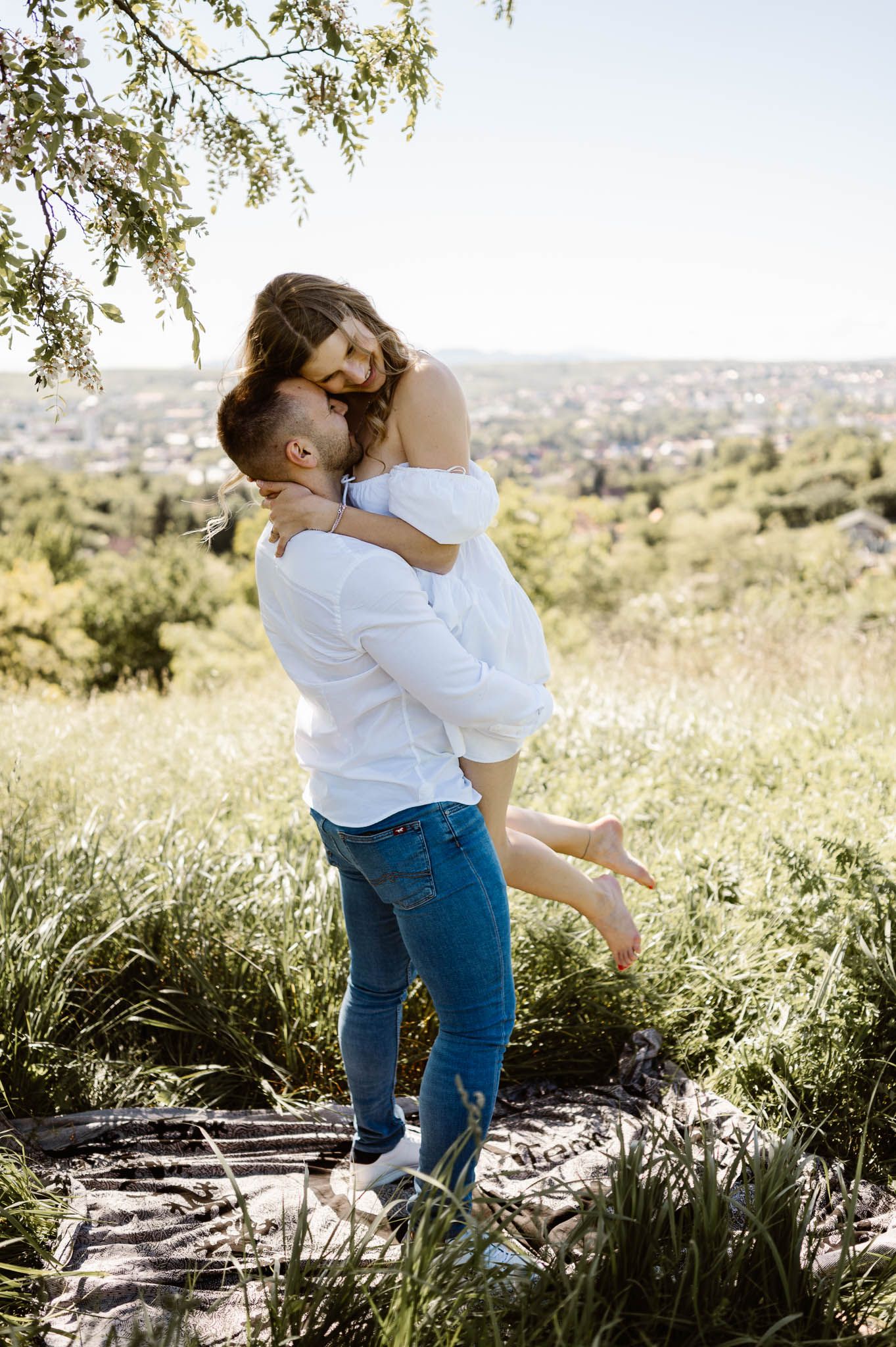Romantic sequence of a couple embracing on a hilltop overlooking a city landscape.