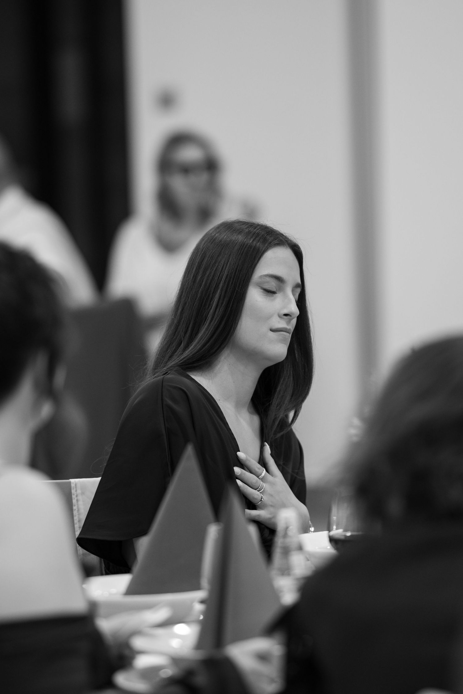 Black and white sequence of a person with long dark hair at a formal dinner event.