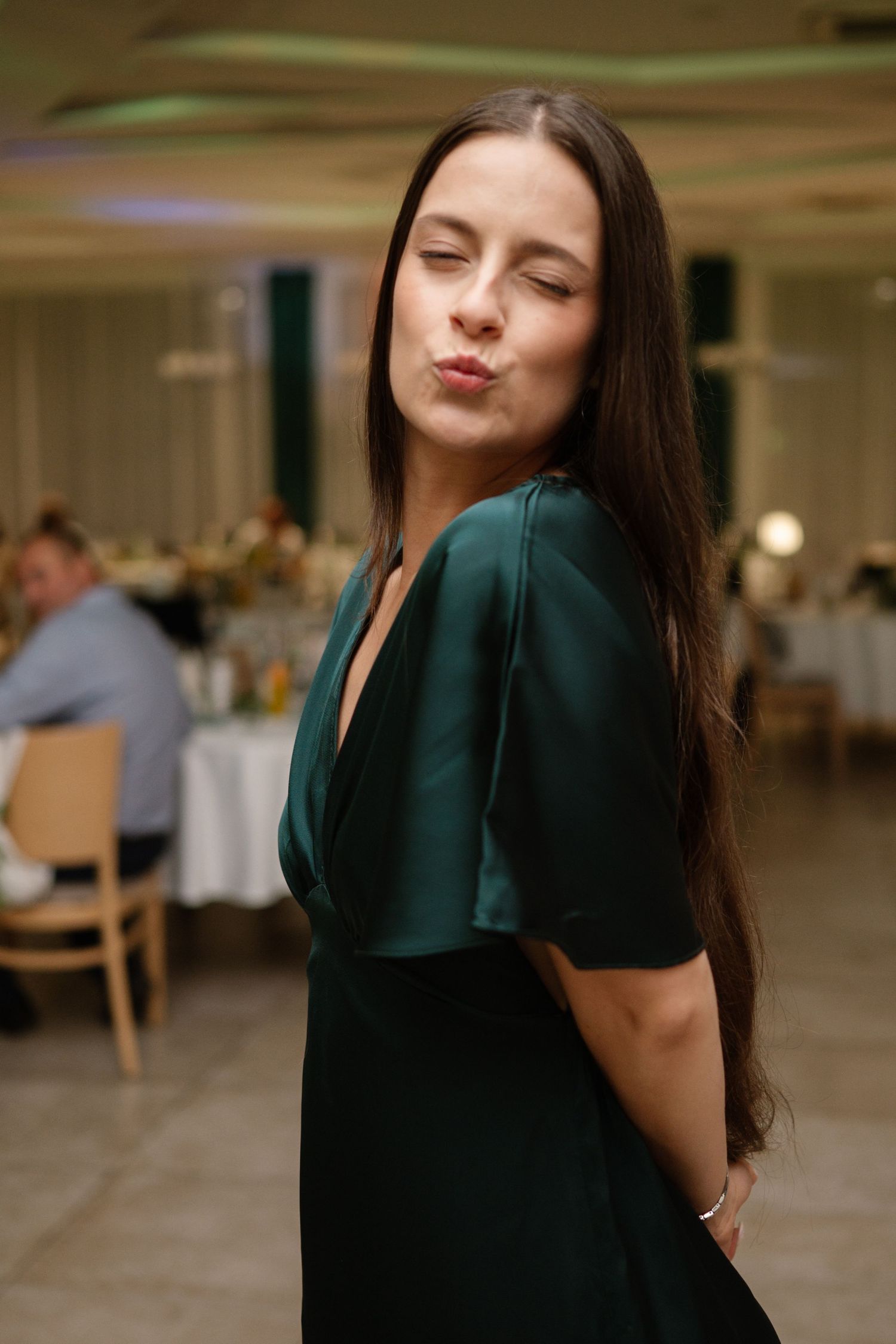 Woman in emerald green dress posing in an indoor venue setting.