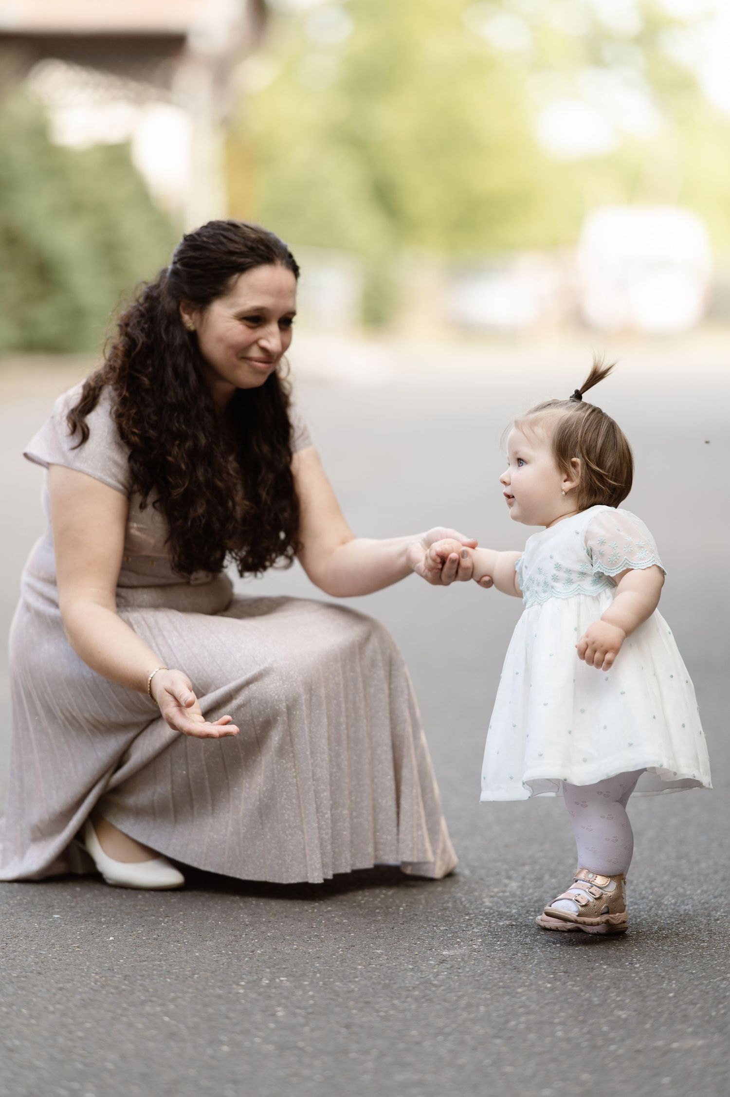 Sweet interaction between a bridesmaid and young flower girl on pavement.