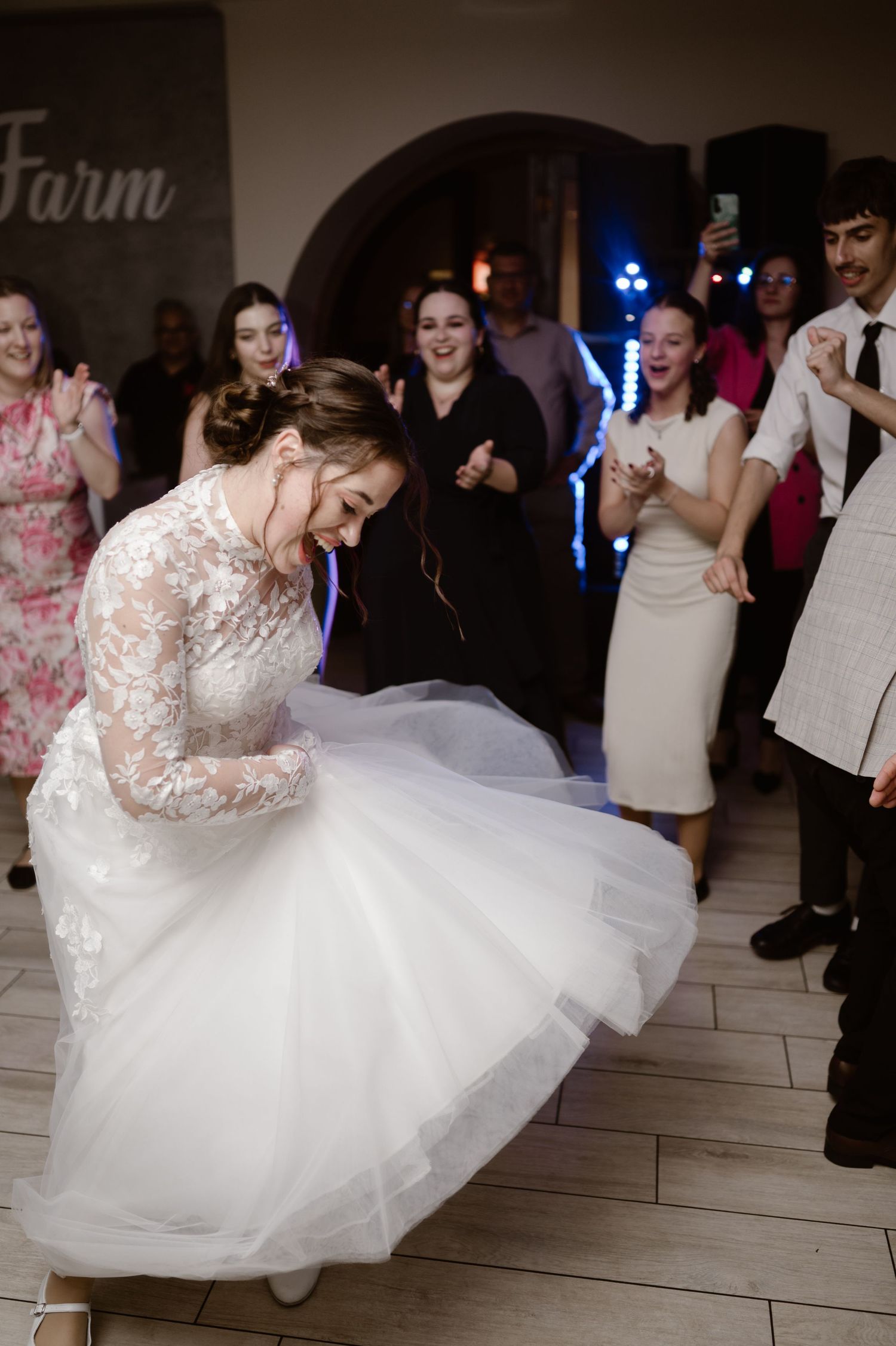 A bride in a white lace gown twirls on the dance floor during her wedding reception.