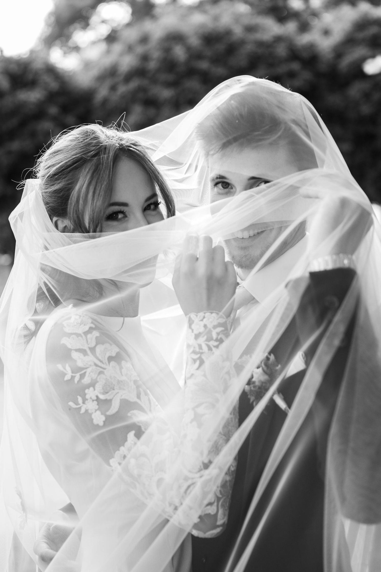 A flowing white wedding veil creates an ethereal effect in a series of black and white photographs.