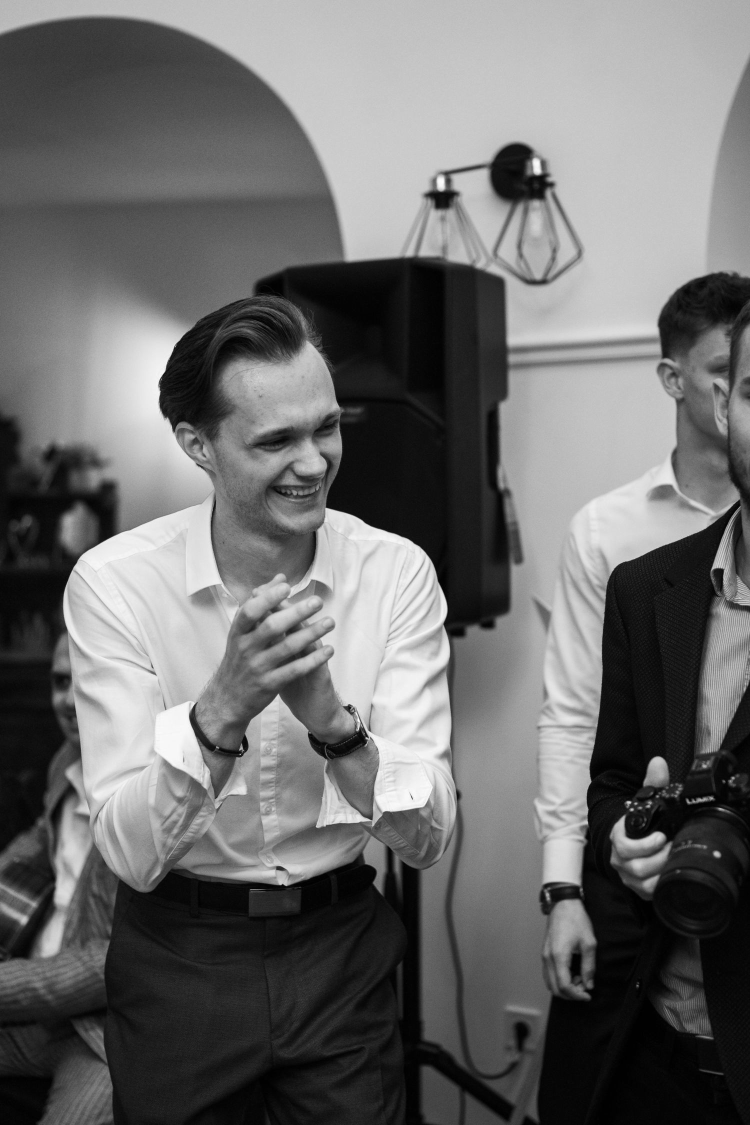 Black and white photo of guests laughing during wedding celebration.