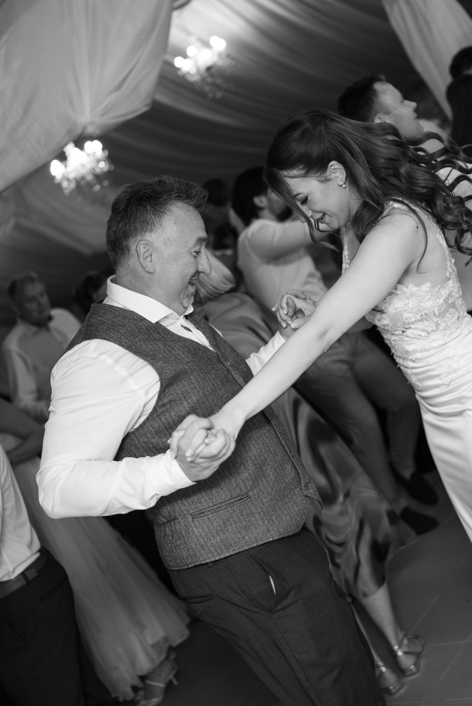 Black and white photo of a bride and groom sharing a joyful dance together at their wedding reception.