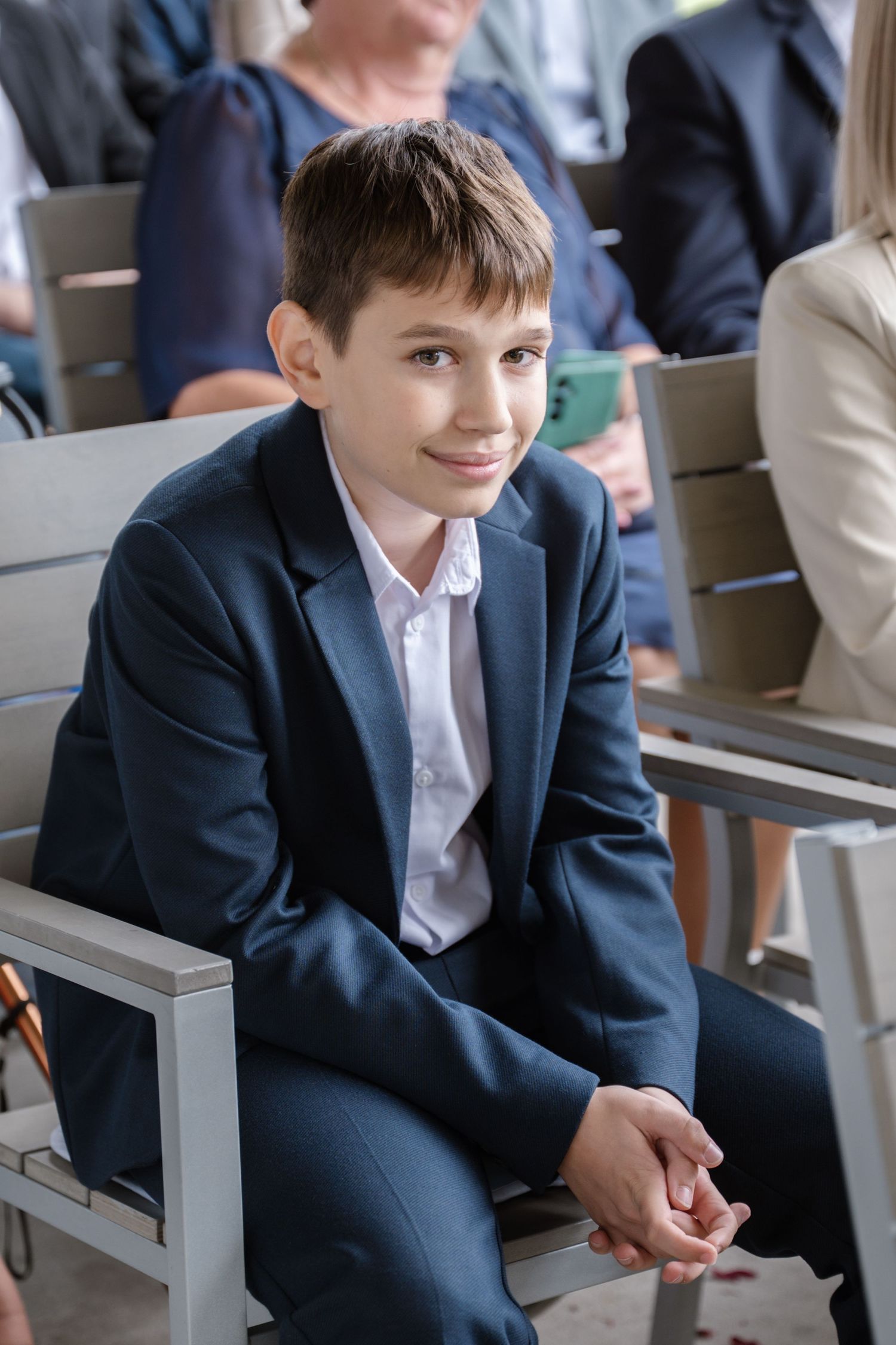 Young attendee in navy suit sitting on modern grey chairs.