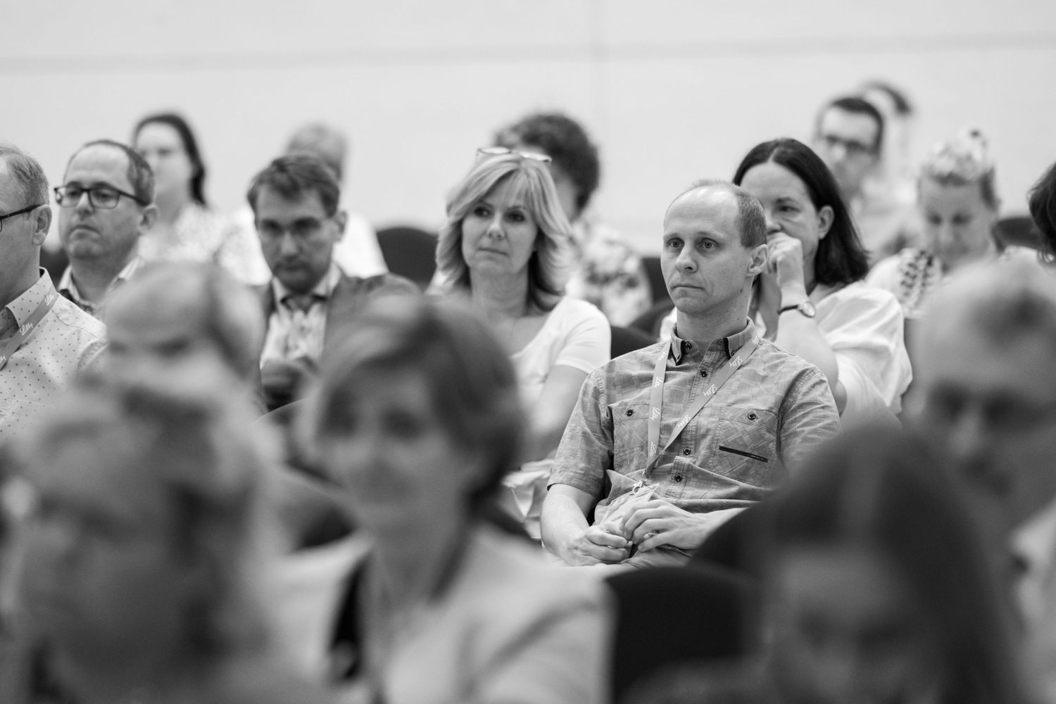 Black and white image of audience members attentively watching presentation.