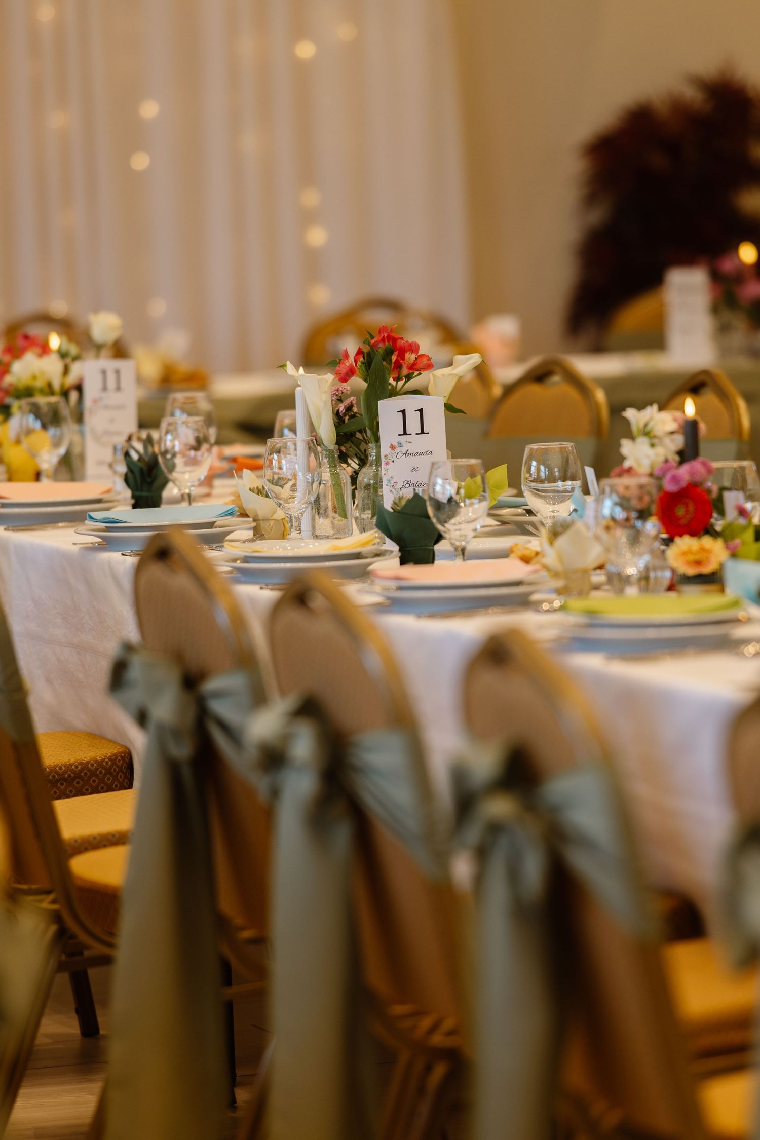 Elegant wedding reception tables set with white linens, floral centerpieces, and place settings in a formal dining room.