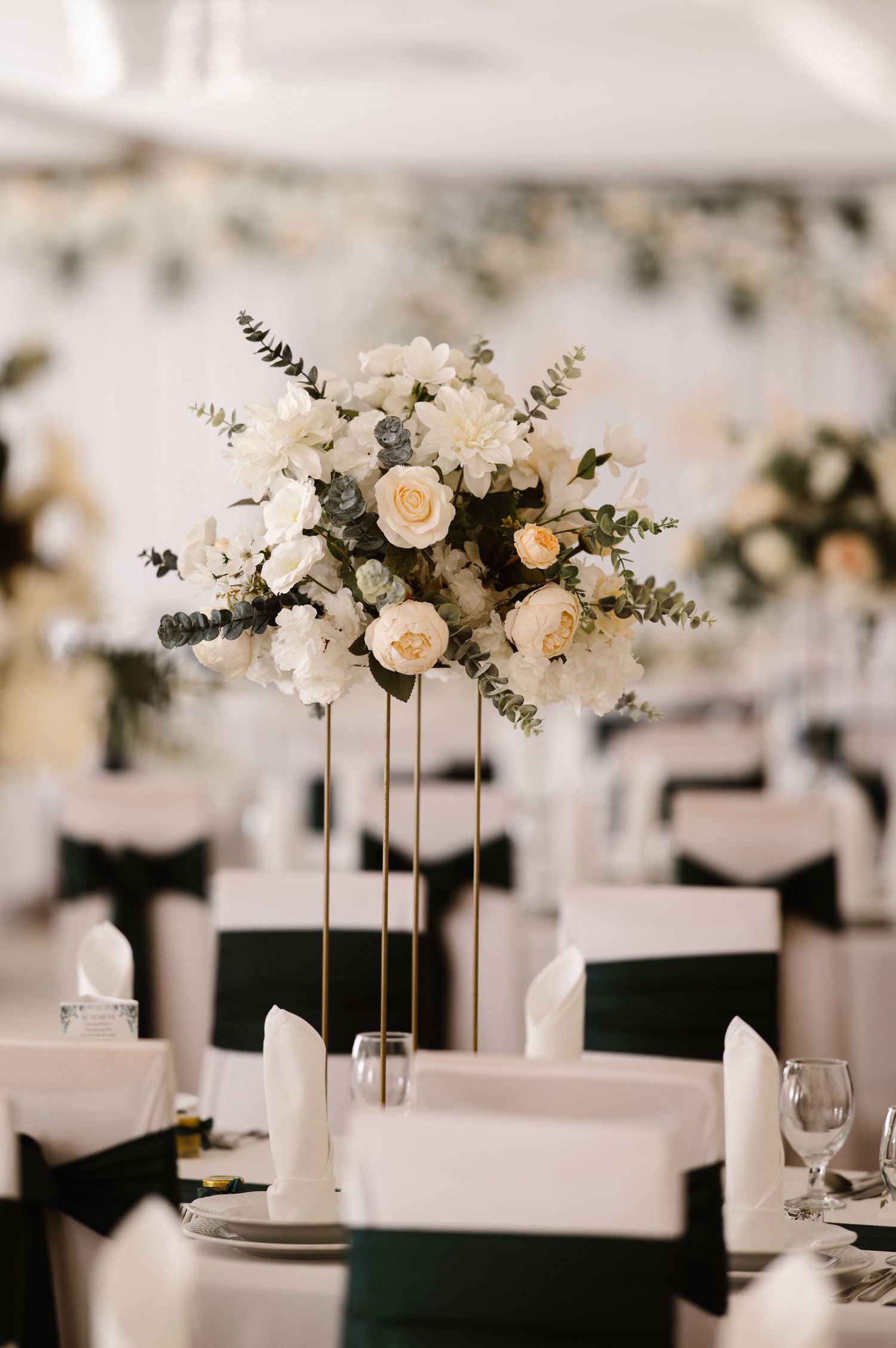 Elegant white floral centerpieces on long reception tables with black linens.