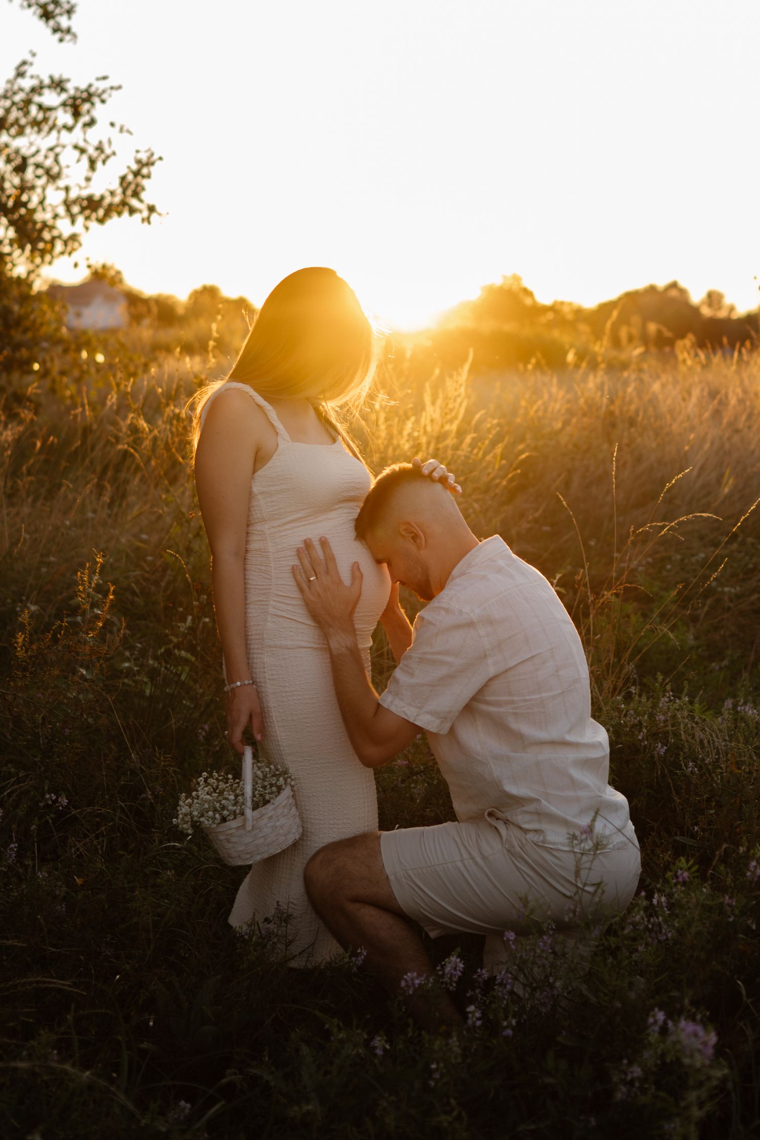 Intimate sunset photoshoot in a golden field with warm backlighting.