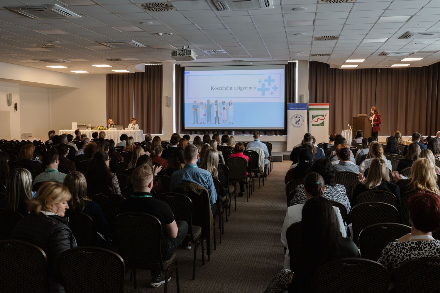 Large conference room filled with attendees watching a presentation in a corporate setting.