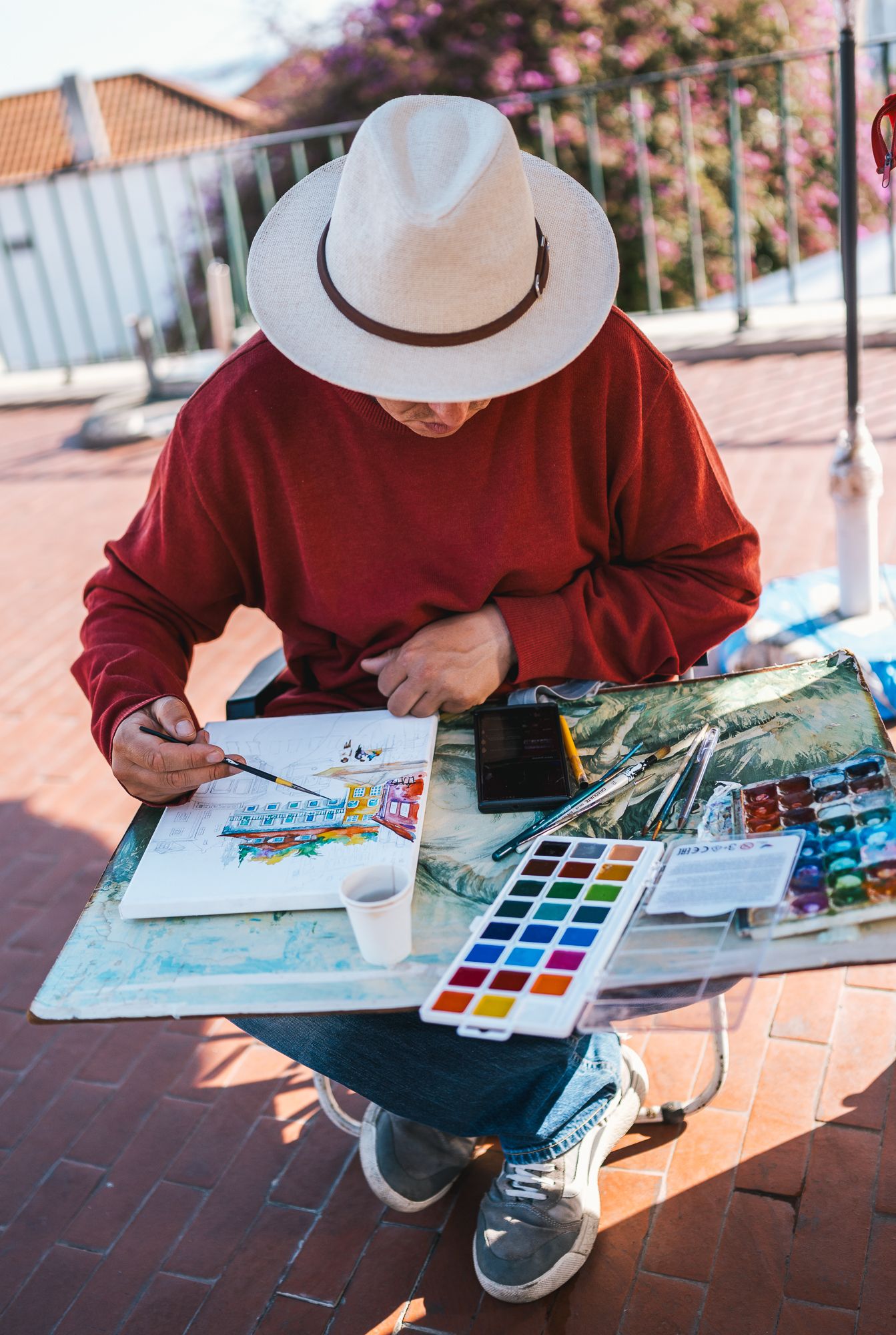 Artist painting with watercolors while sitting outdoors on a sunny day.