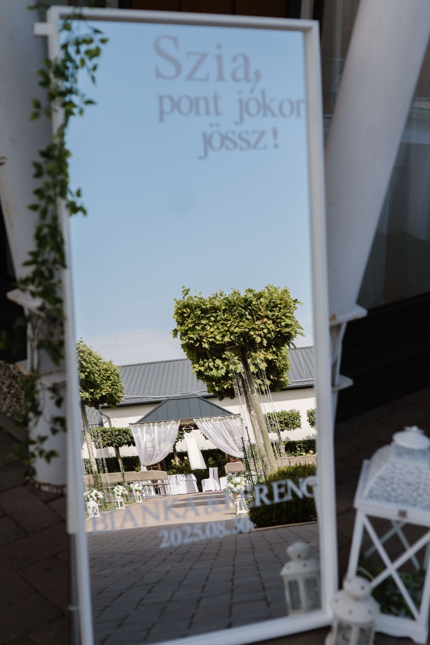 Wedding welcome sign with reflective surface showing venue exterior.