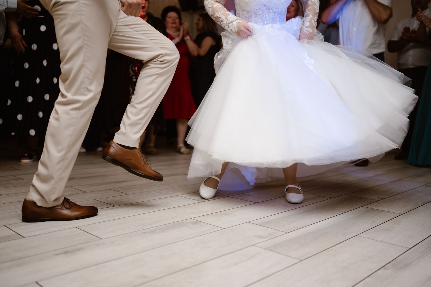 Dancers' feet move across a white dance floor during an upbeat wedding reception.