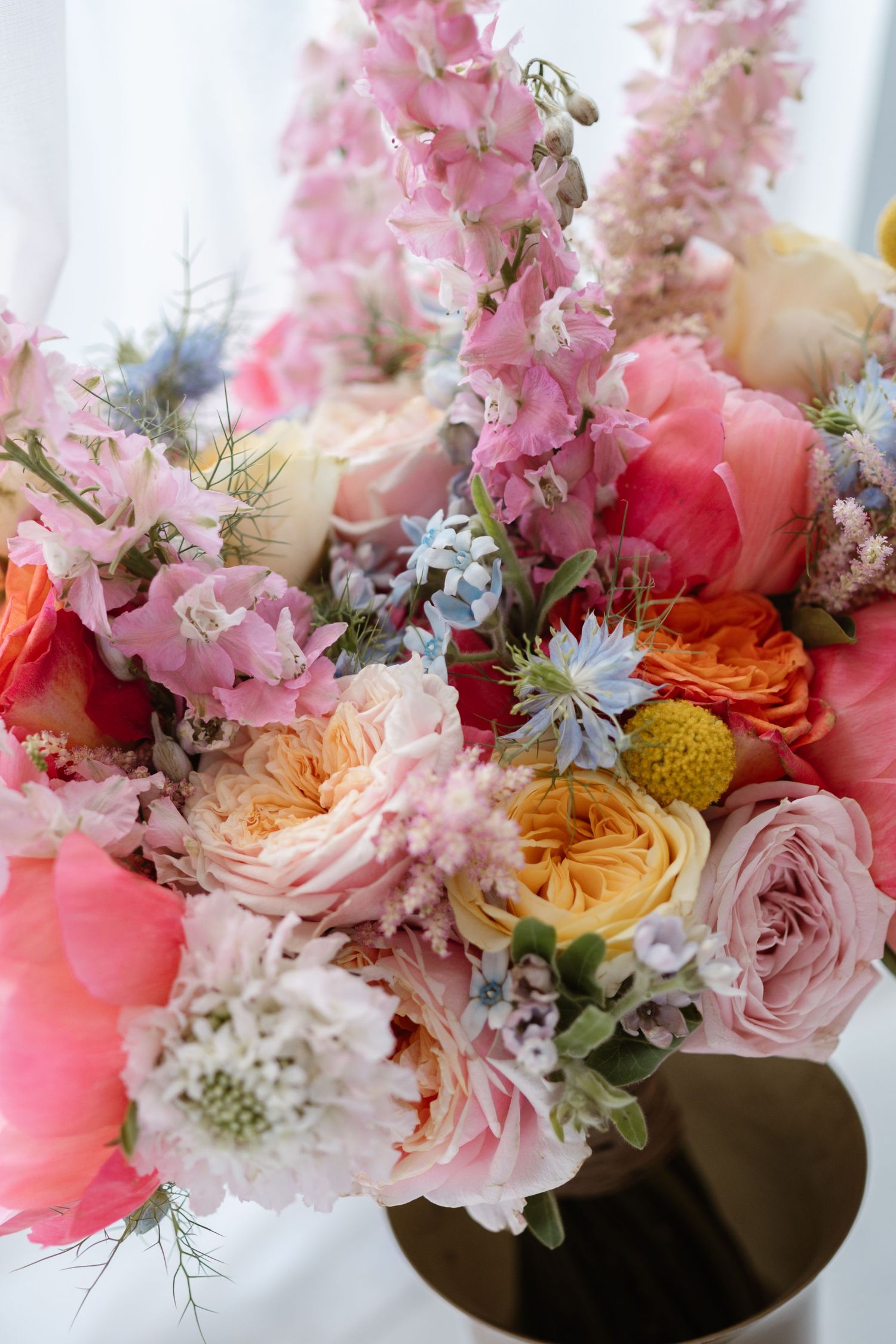 Stunning floral arrangement with pink, coral and white blooms including roses and daisies.
