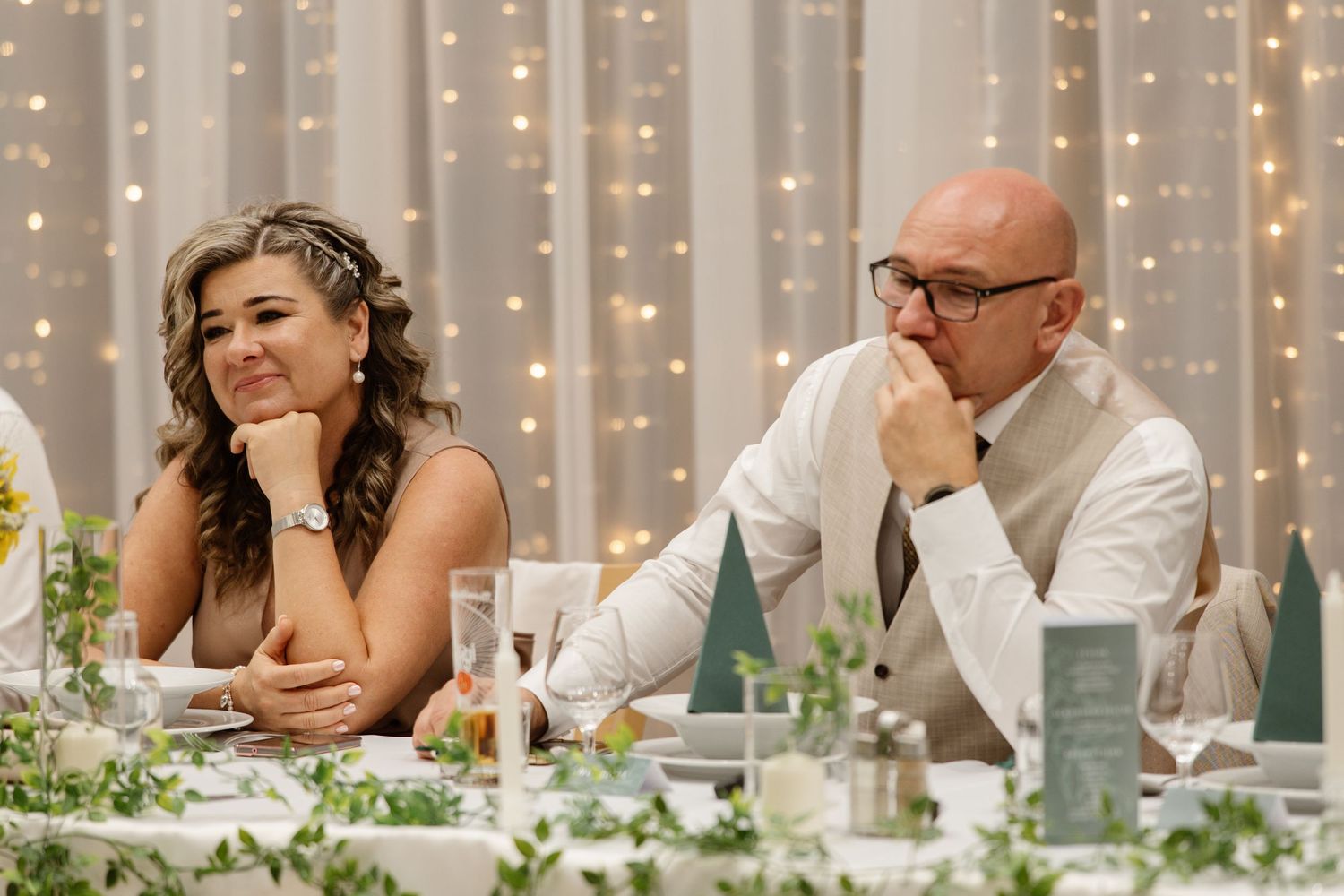Wedding reception table setting with string lights and white decor creating romantic ambiance.