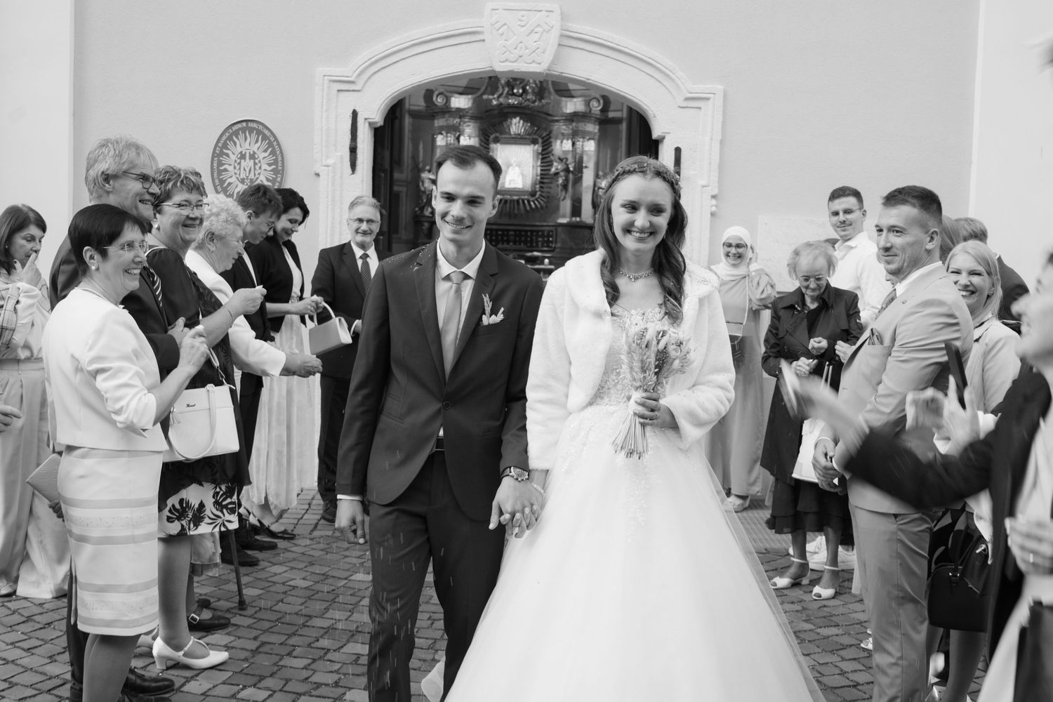 Black and white photo of wedding guests forming a receiving line outside a church.