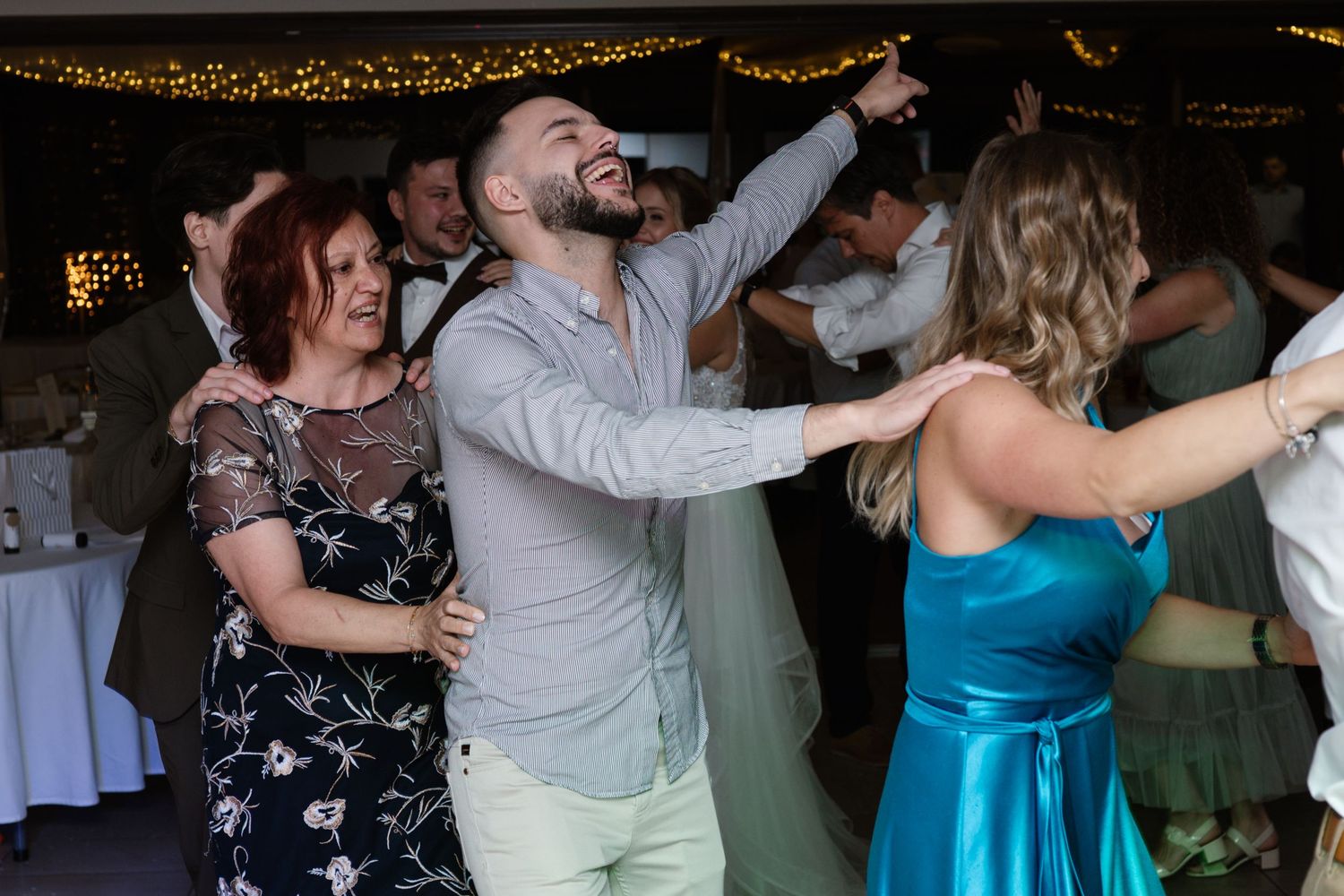 Wedding reception dance floor filled with guests dancing under string lights.