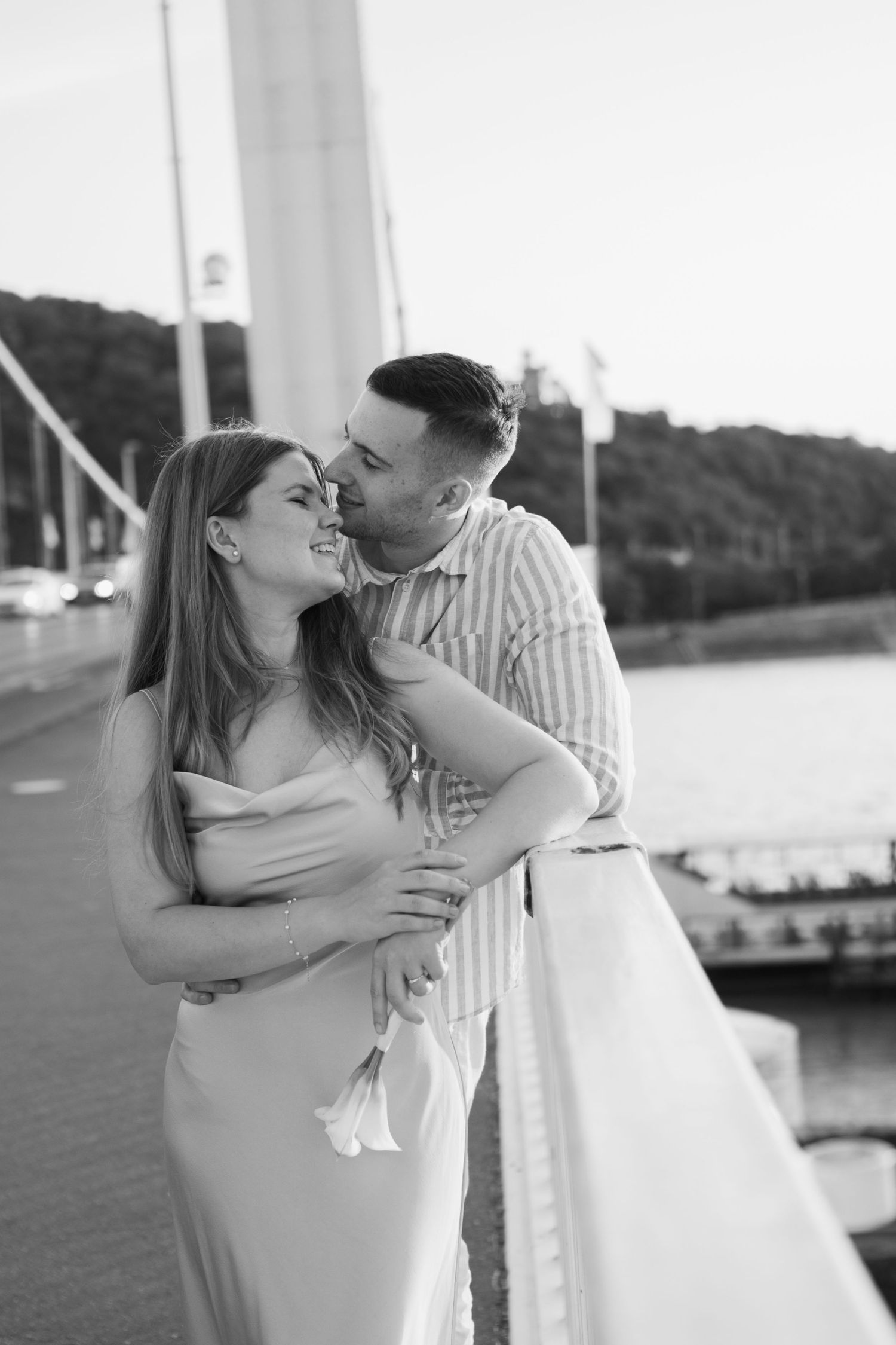 Couple sharing tender moment on waterfront with boats in background.