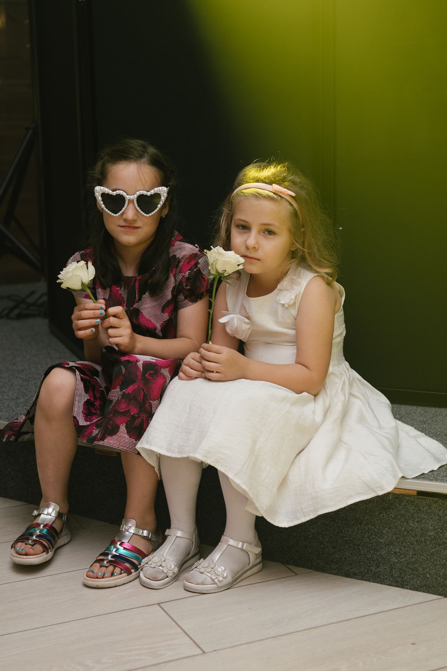 Young attendees in formal wear sitting on the ground with flowers.