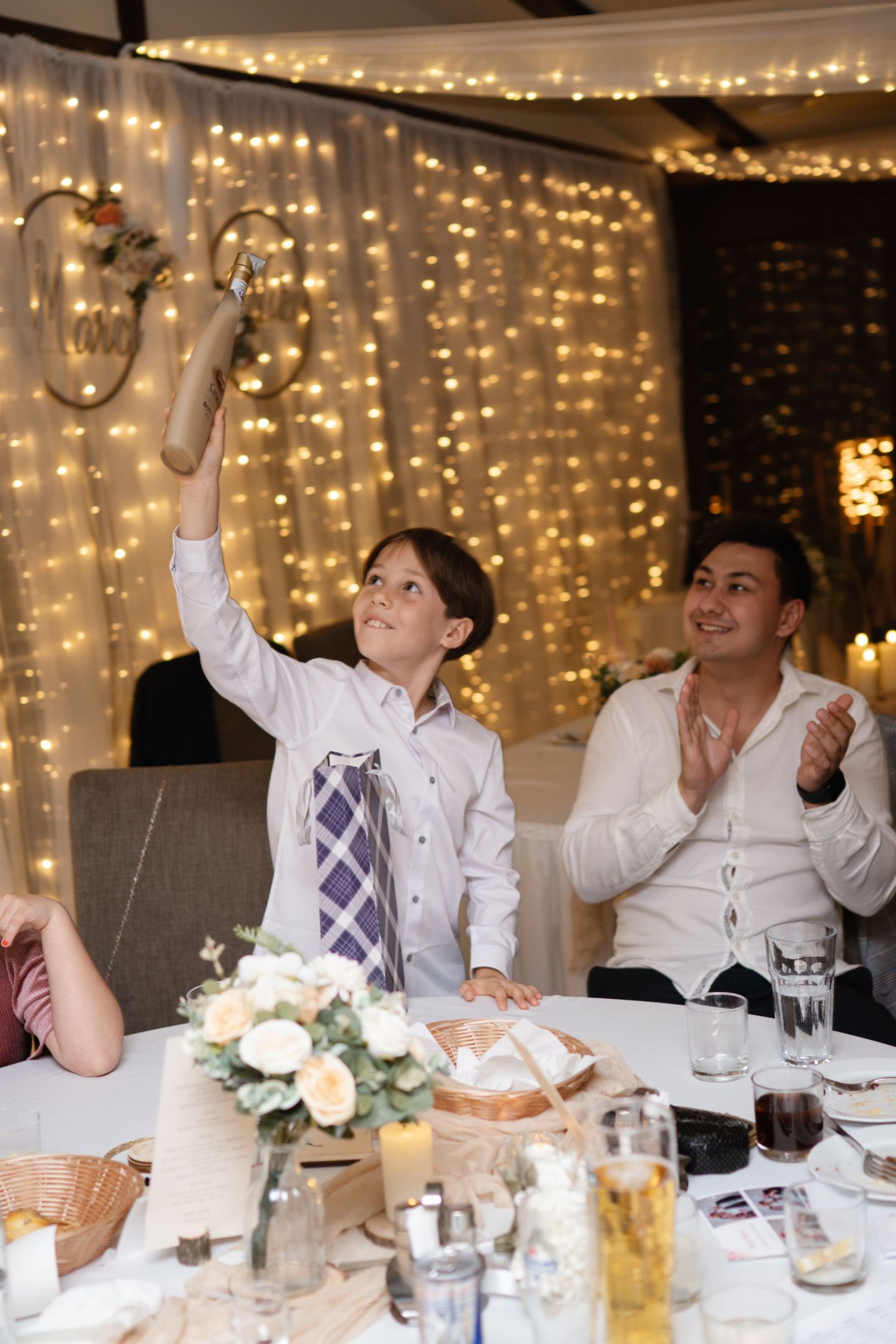 Wedding guests enjoying dinner and conversation under string light decorations.