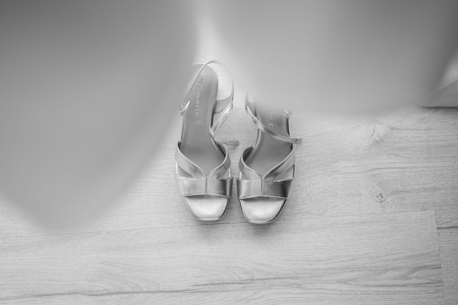 Elegant white bridal shoes arranged on a light wooden surface.
