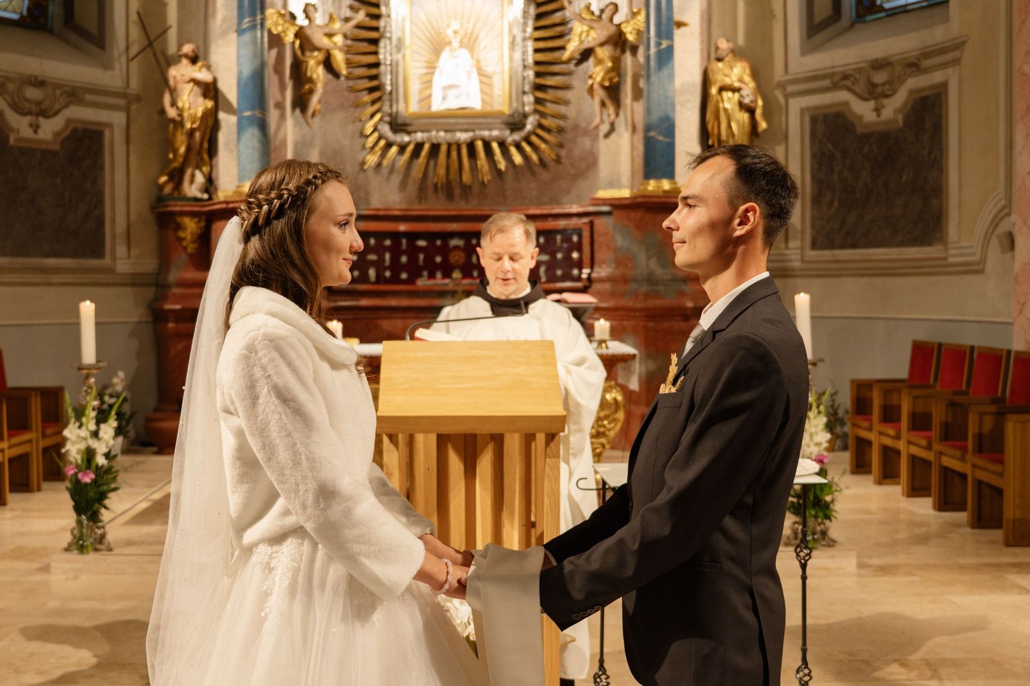 A wedding ceremony taking place at the altar of an ornate church.