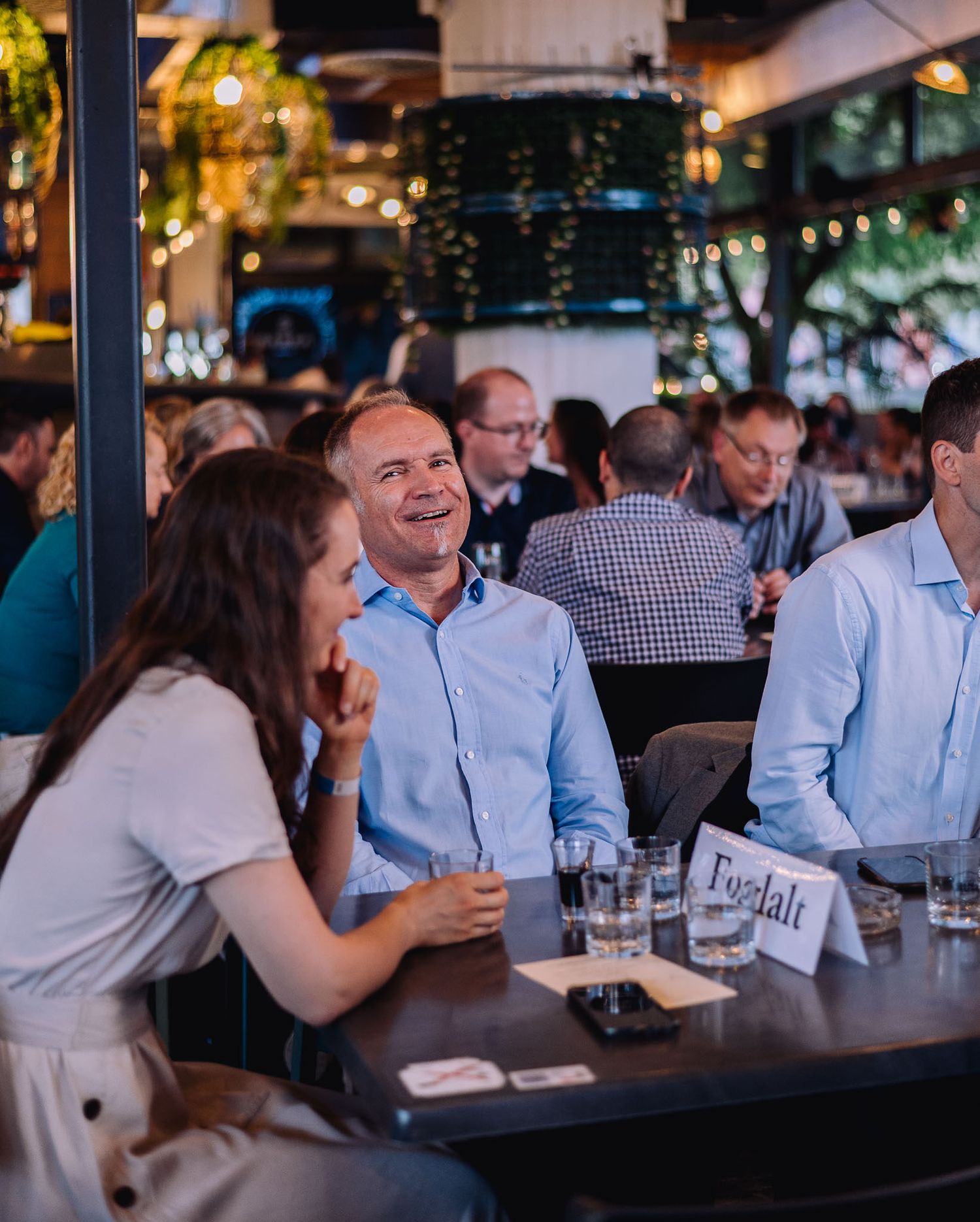 Evening social gathering with attendees enjoying drinks and conversation at an outdoor venue.