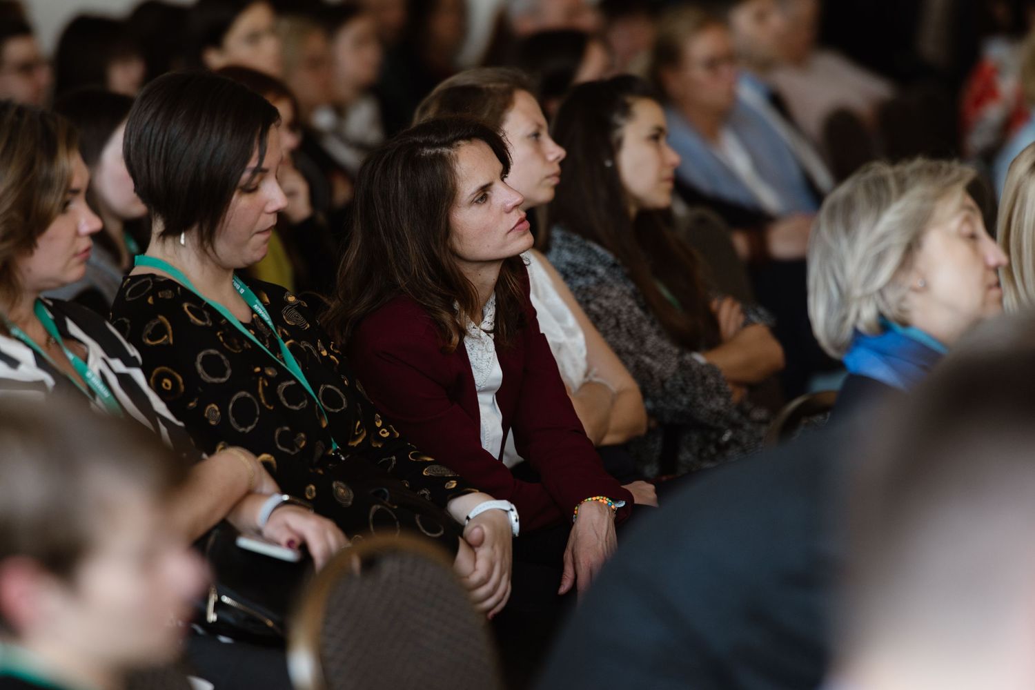 Audience members seated in rows at a dimly lit conference or event venue.
