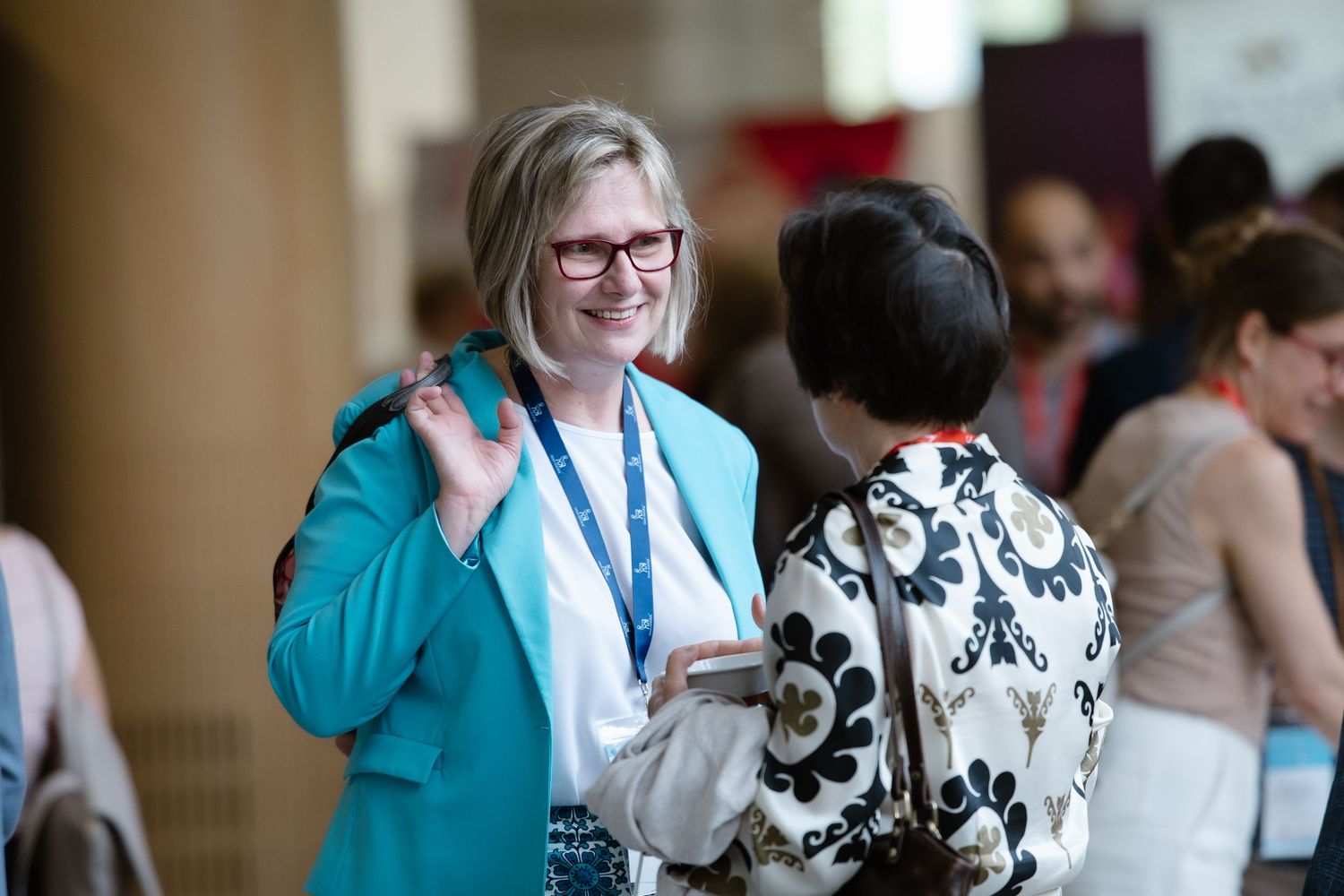 Conference attendees in business attire network and engage in conversation during a professional event.