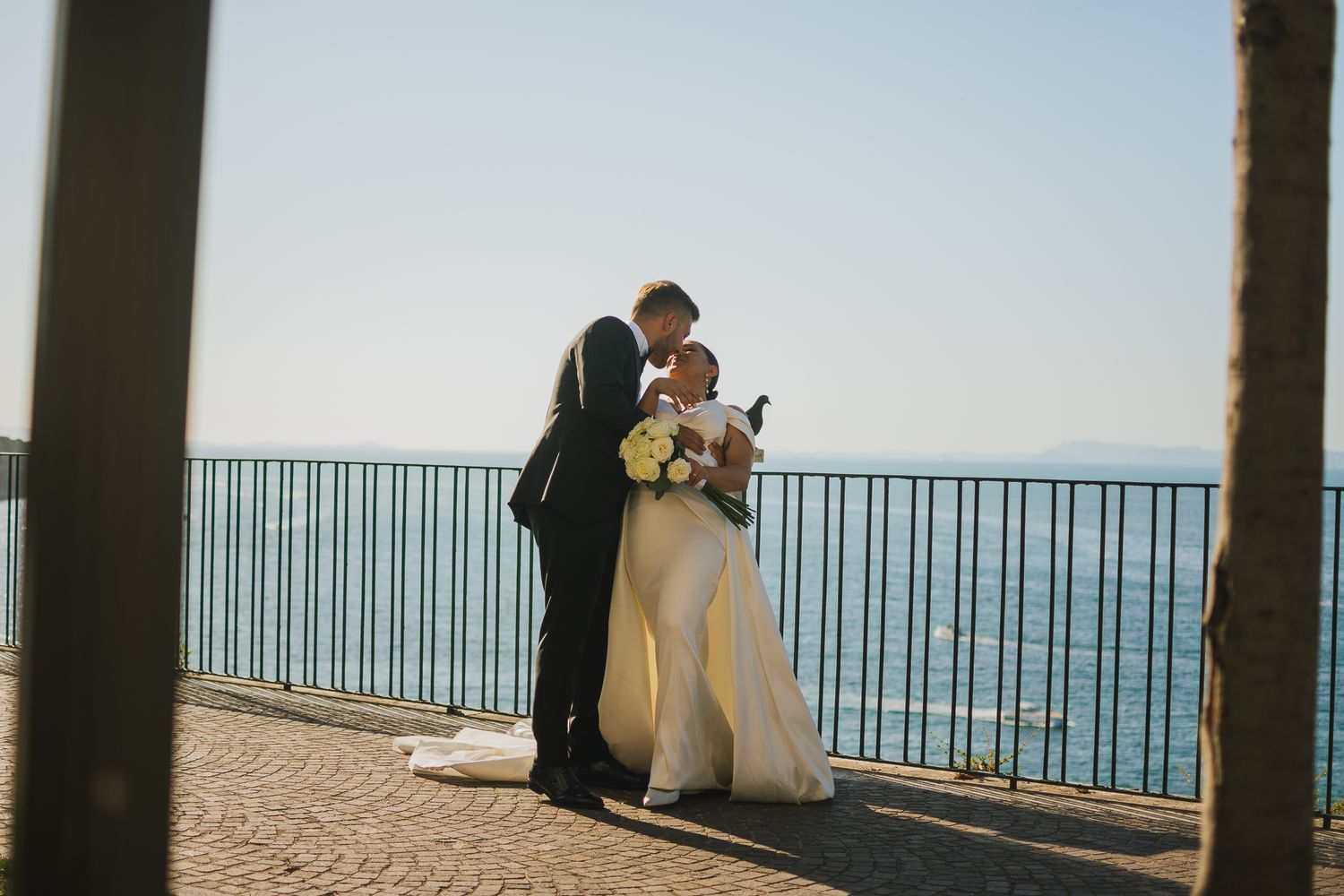Wedding ceremony taking place on an oceanfront terrace with Mediterranean views and white columns.