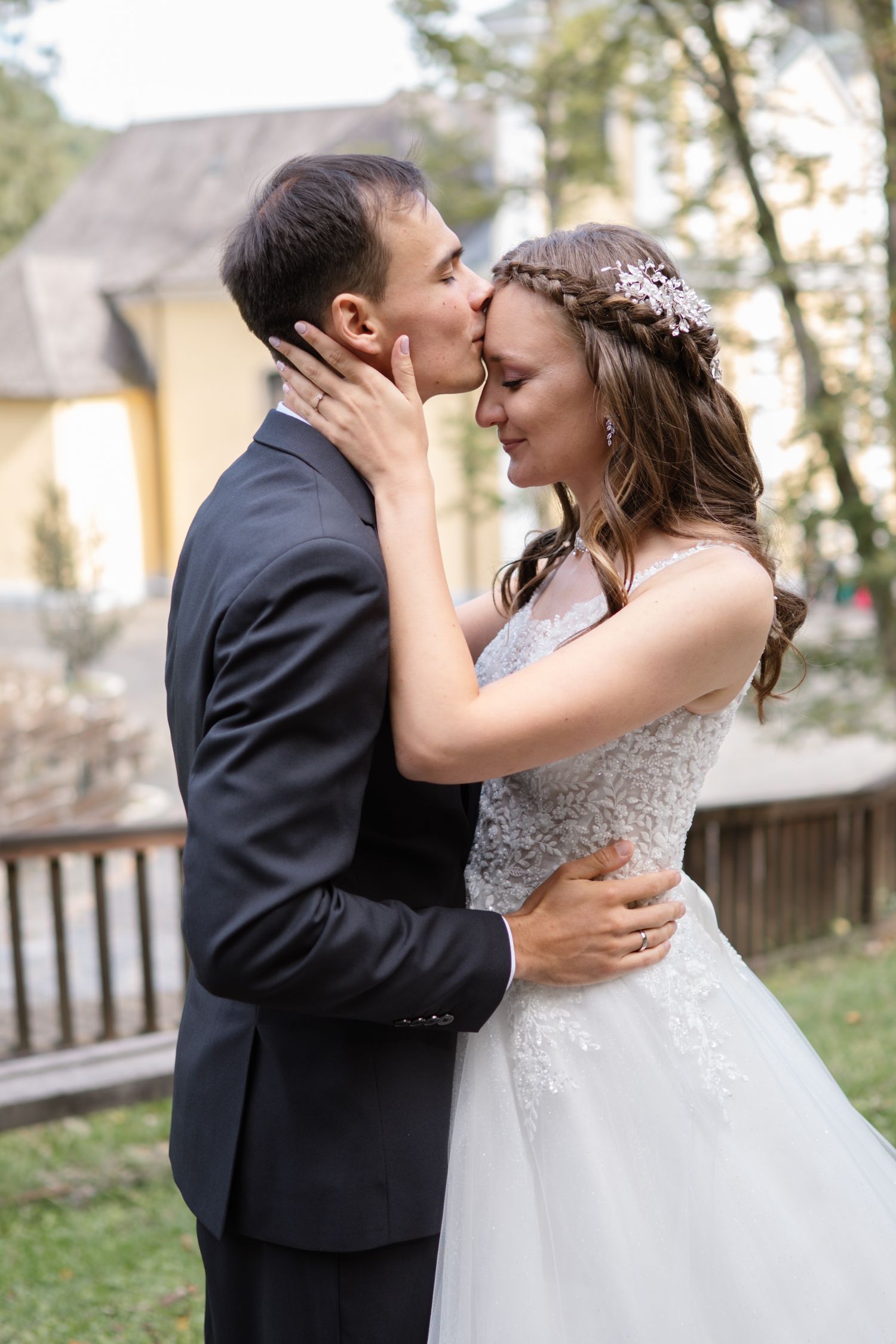 A tender moment between newlyweds wearing bridal attire in an outdoor garden setting.