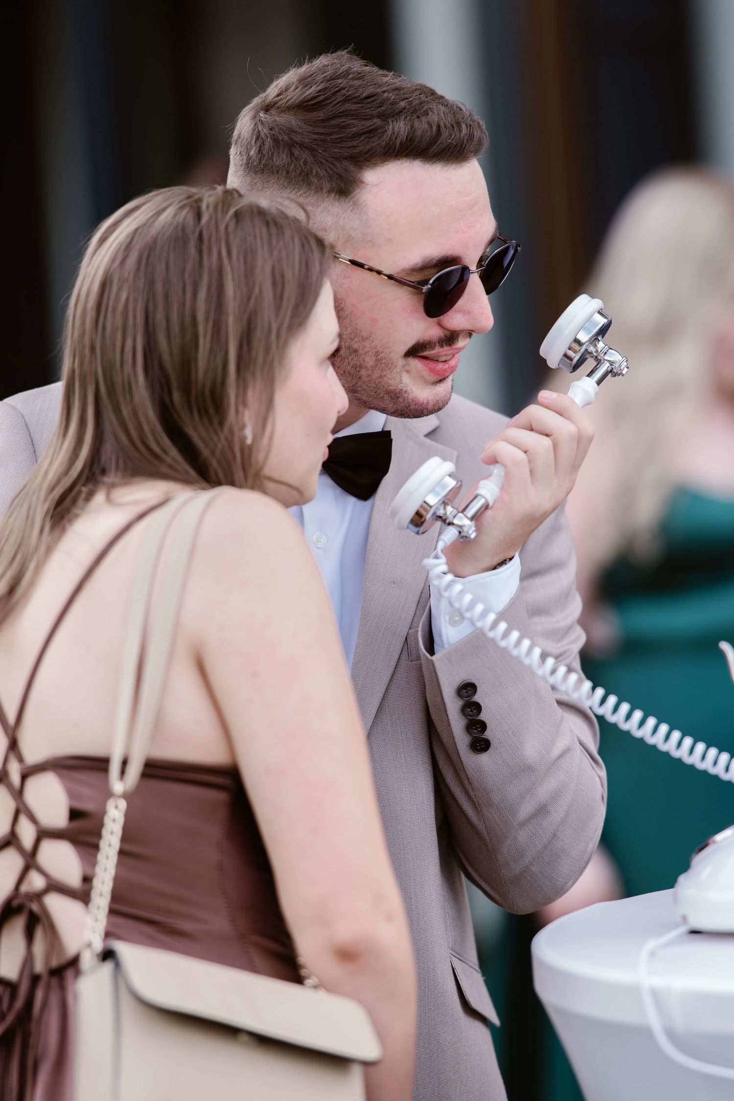 A couple examining vintage telephones at what appears to be an antique display.