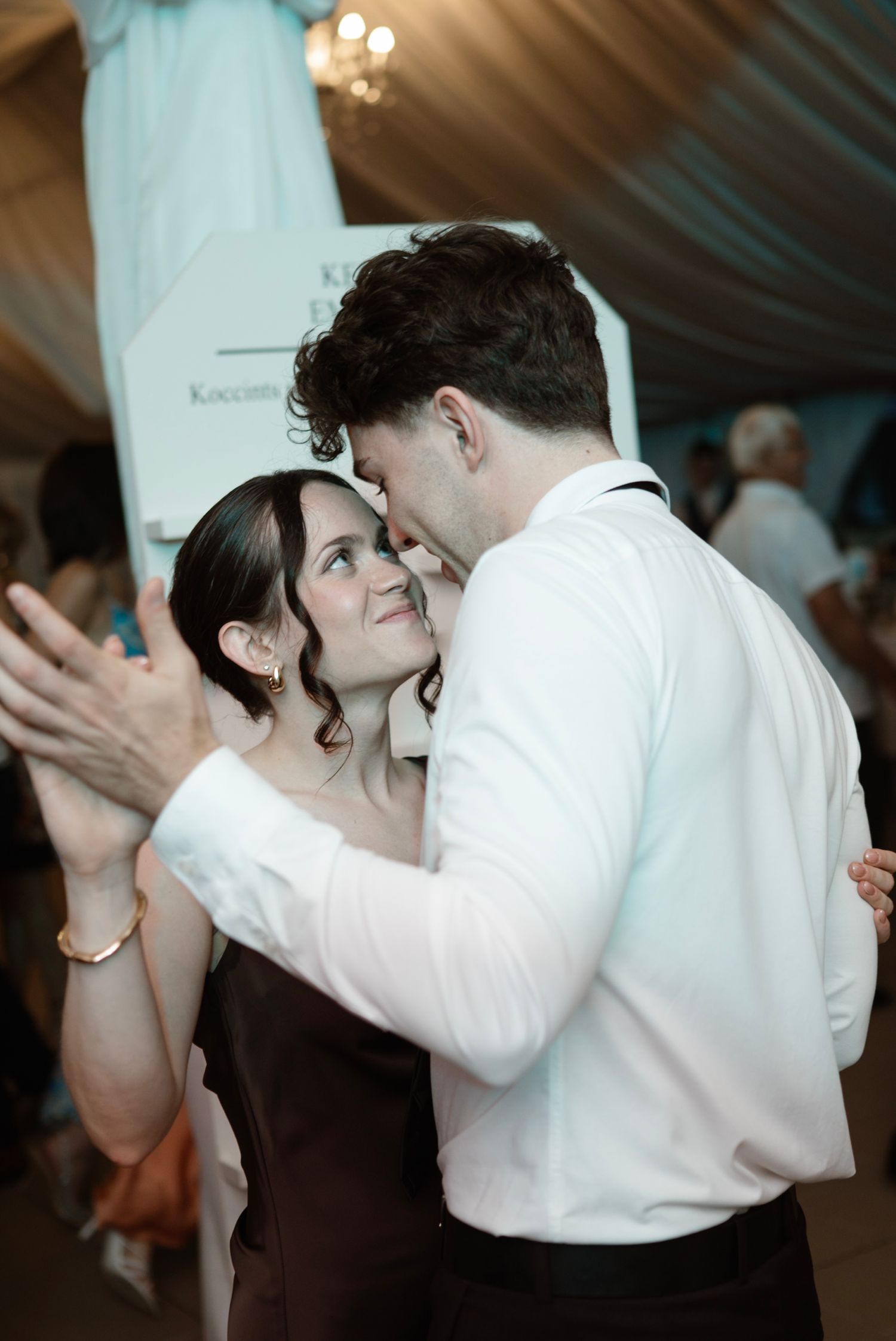 Couple sharing a tender dance moment together at an elegant wedding reception under draped ceilings.