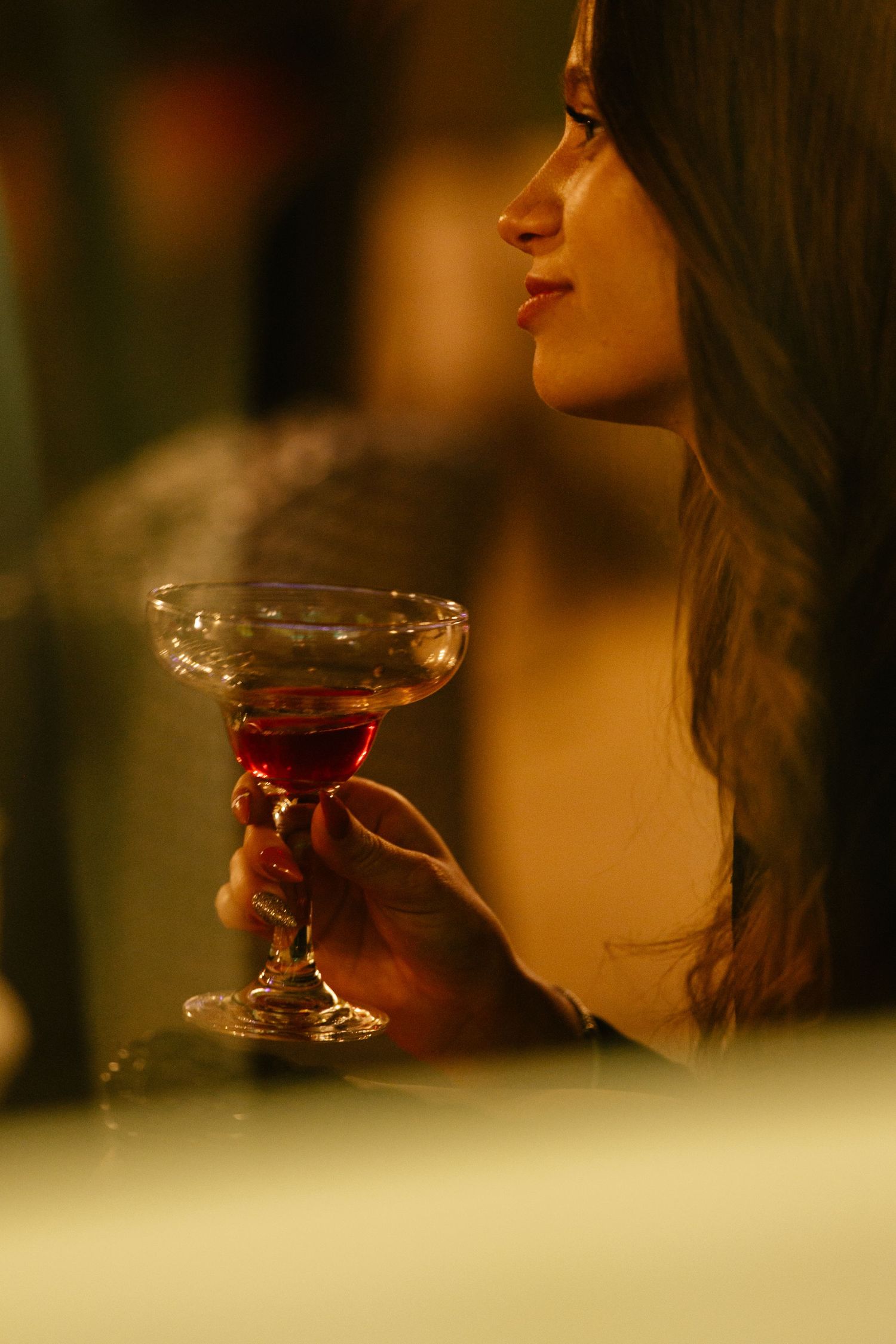 A glass of red wine being sipped in warm ambient lighting.