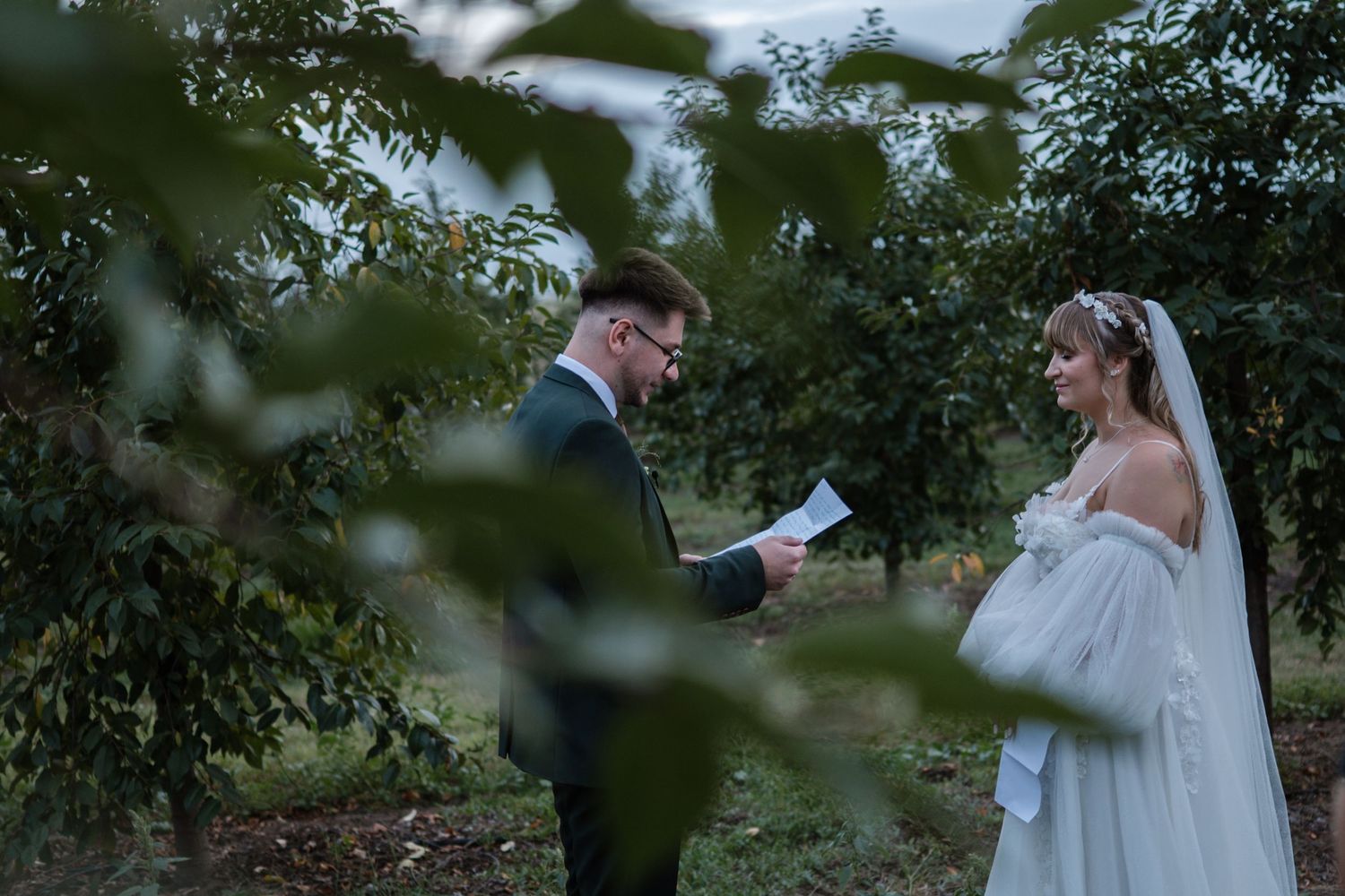 Romantic wedding photos captured through tree branches in natural lighting.