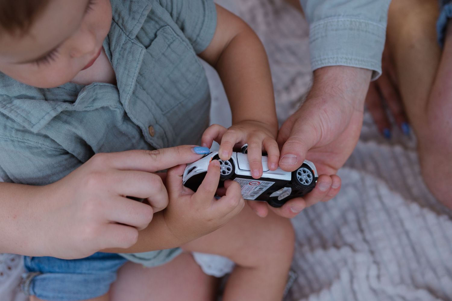Small hands examine a toy car in close-up detail.
