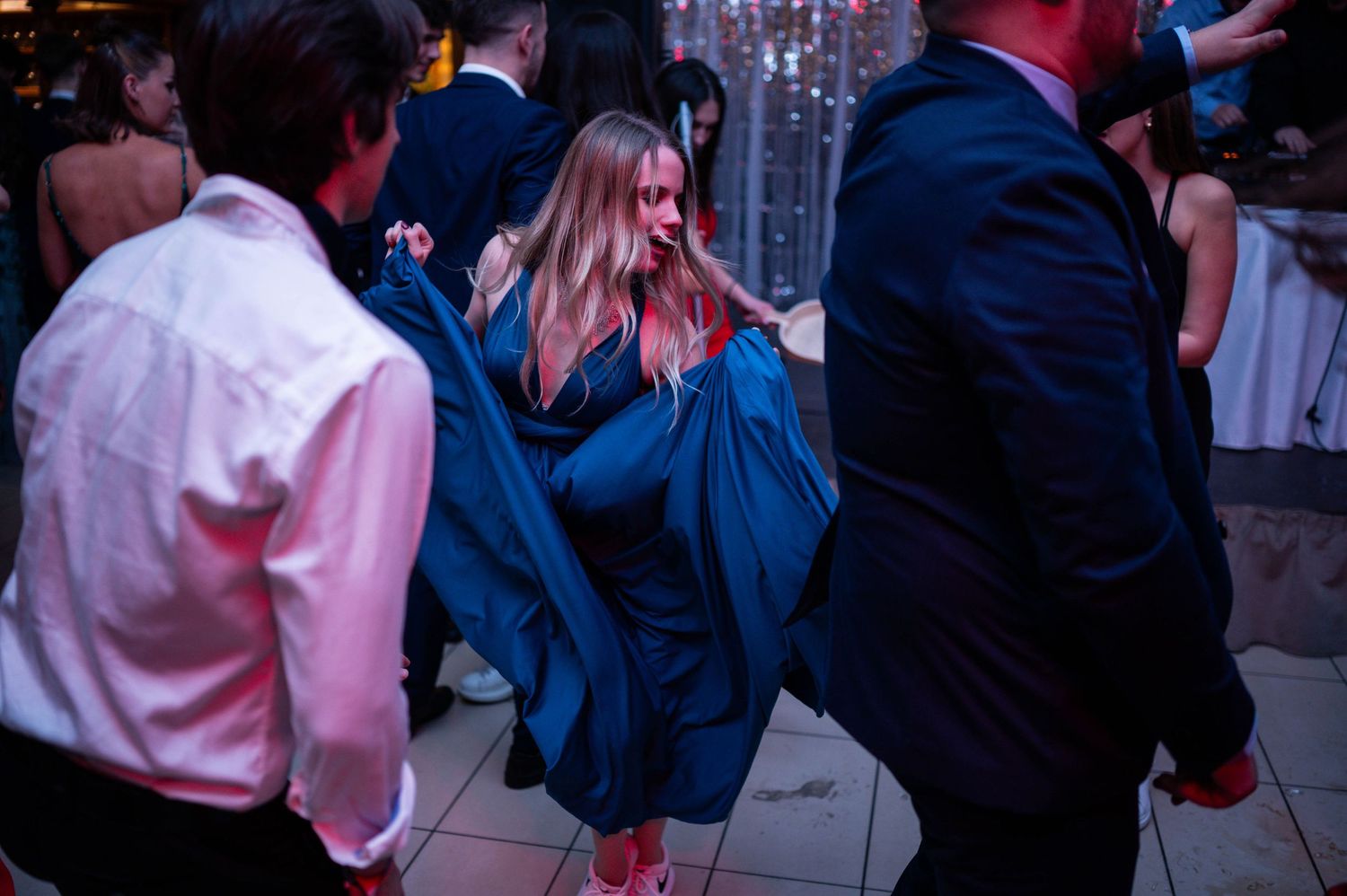 Lively wedding reception dance floor with guests enjoying themselves under decorative lighting.