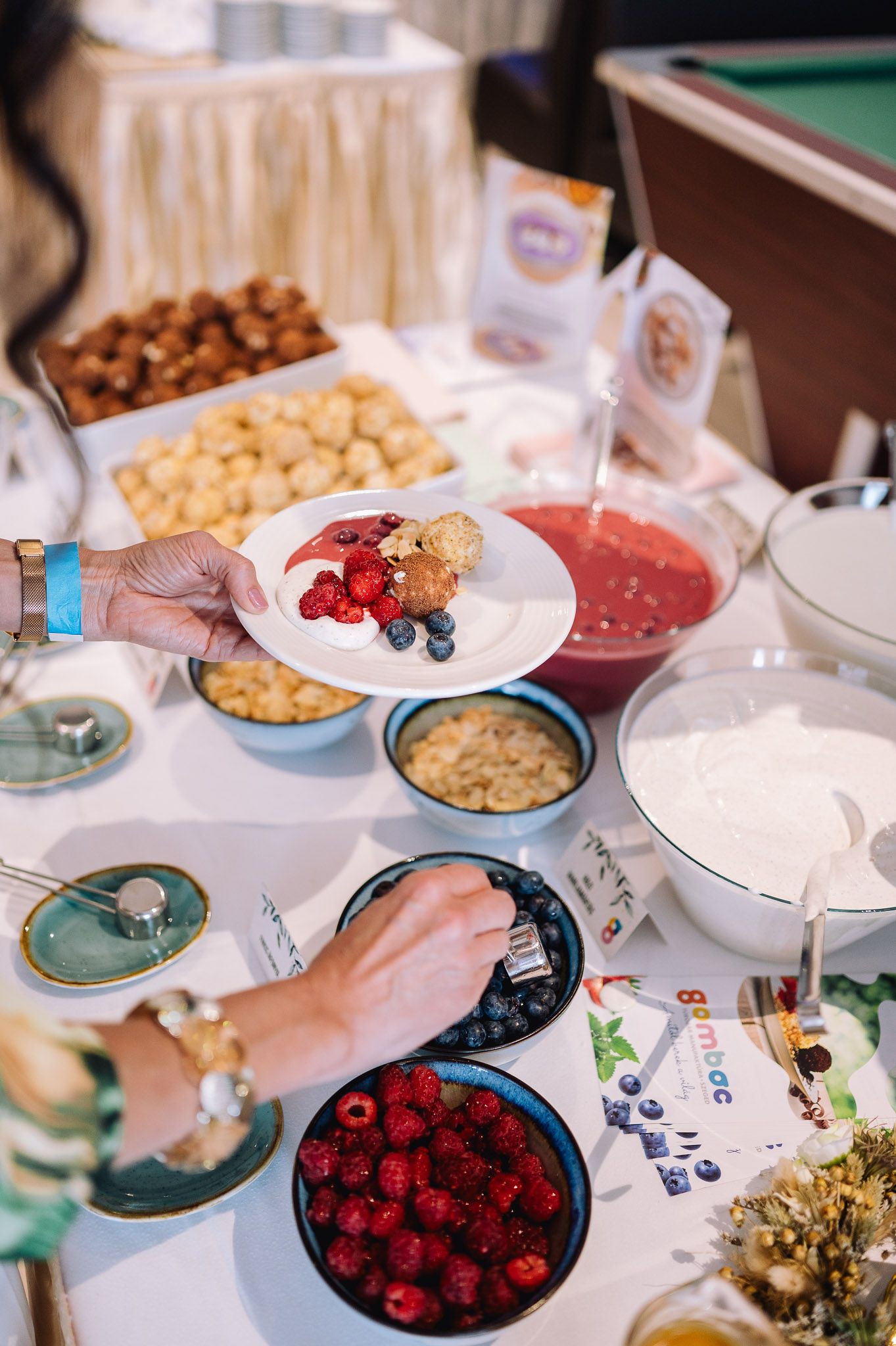Catering spread with fresh berries, nuts and appetizers served on decorative plates.